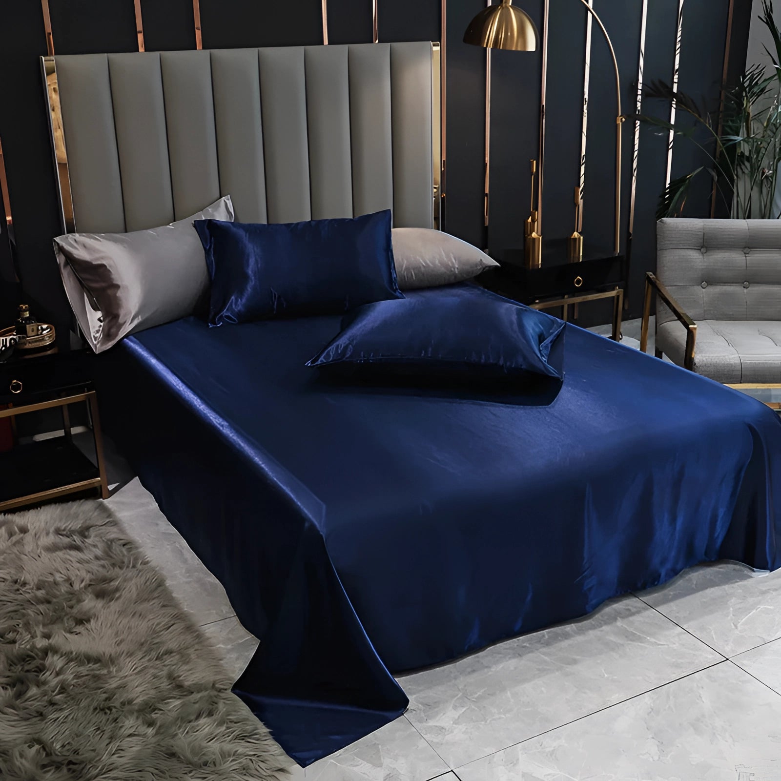 Elegant dark blue satin bedding set in a spacious room, featuring a luxurious silk duvet cover and matching pillowcases on a wooden bed frame.