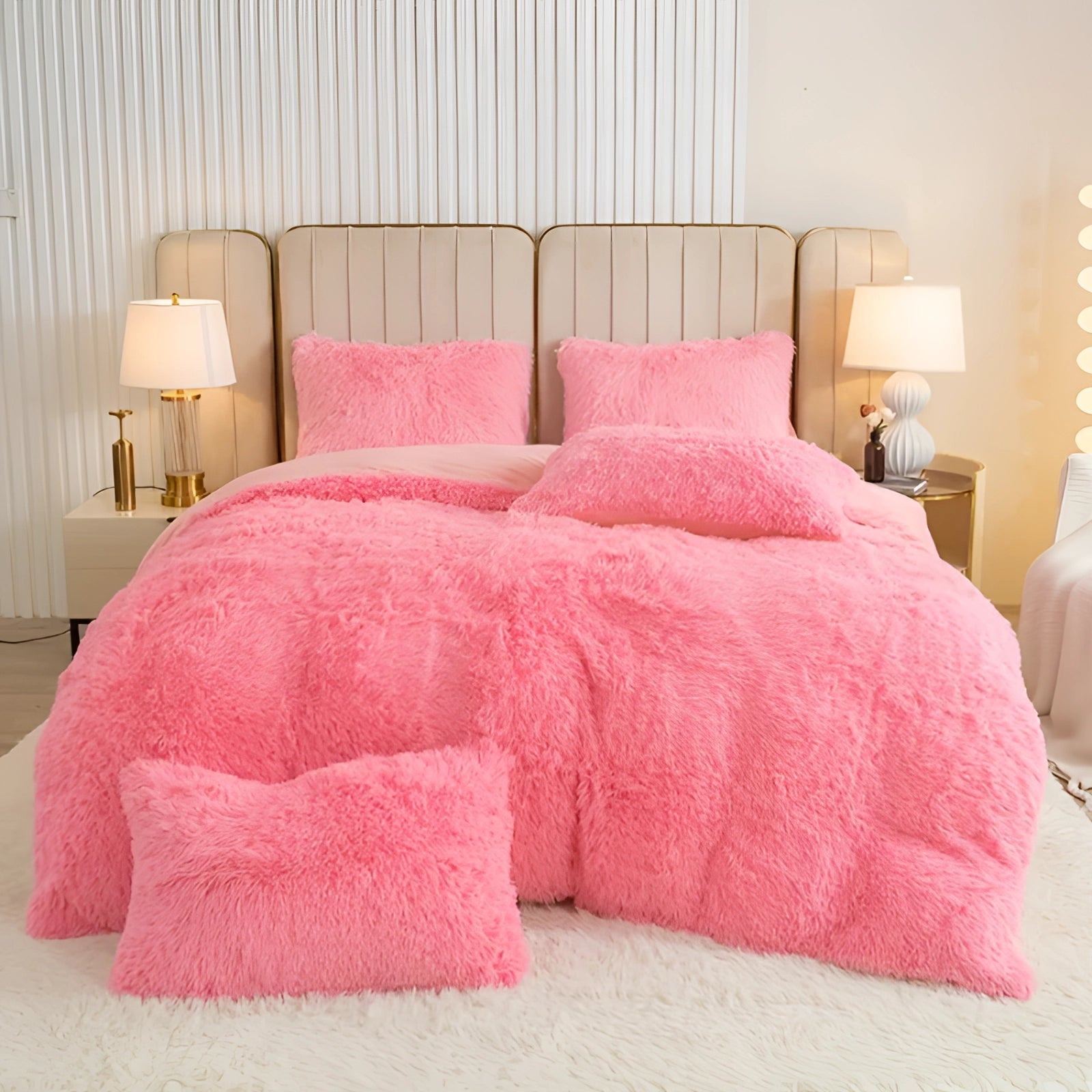 Luxury dark grey faux fur bedding set on a superking bed, featuring a plush comforter and shams in a pink variant. The bed is part of a stylishly furnished bedroom with a wooden bed frame, pillows, a decorative bed skirt, and a nearby lamp, creating a cozy and comfortable interior design.
