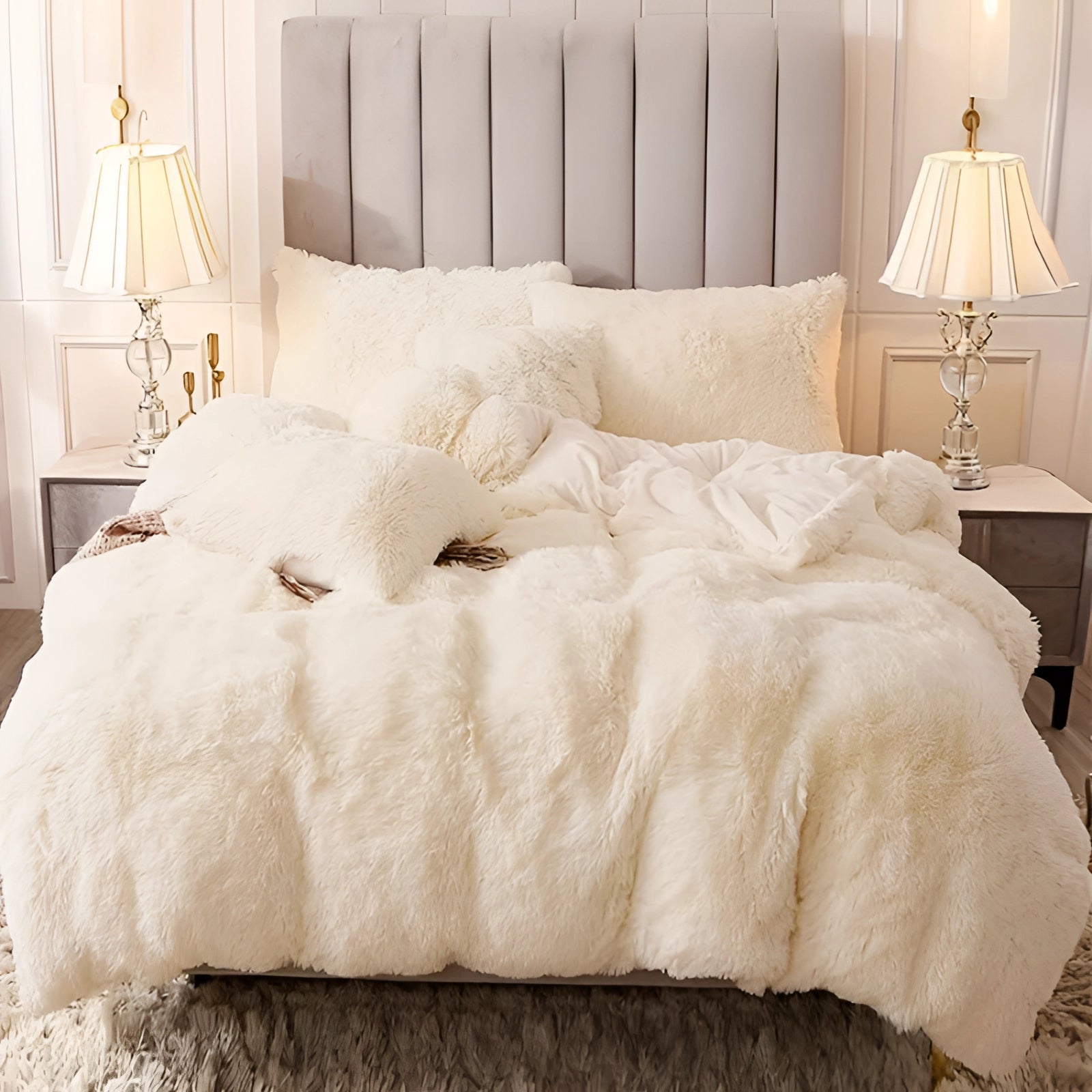 Luxury dark grey faux fur bedding set displayed on a bed, featuring a plush comforter and matching shams in a superking size with cream accents, surrounded by neutral-toned decor including beige pillows, a lamp, and wooden furniture on light flooring.