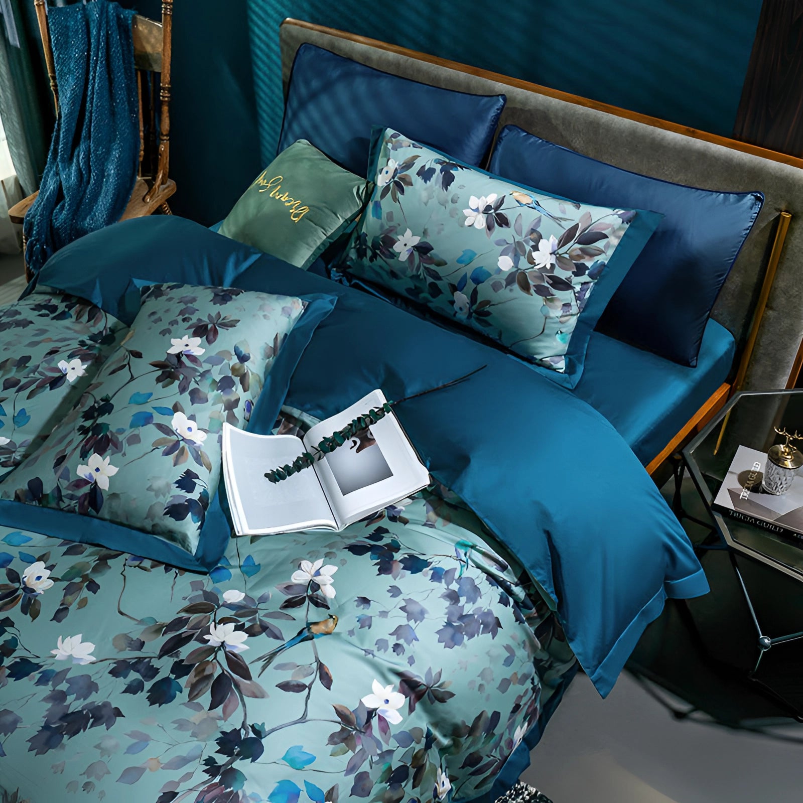 Luxury floral bedding set featuring designer botanical sheets in shades of green and blue with silk pillowcases, displayed in a stylish interior setting.