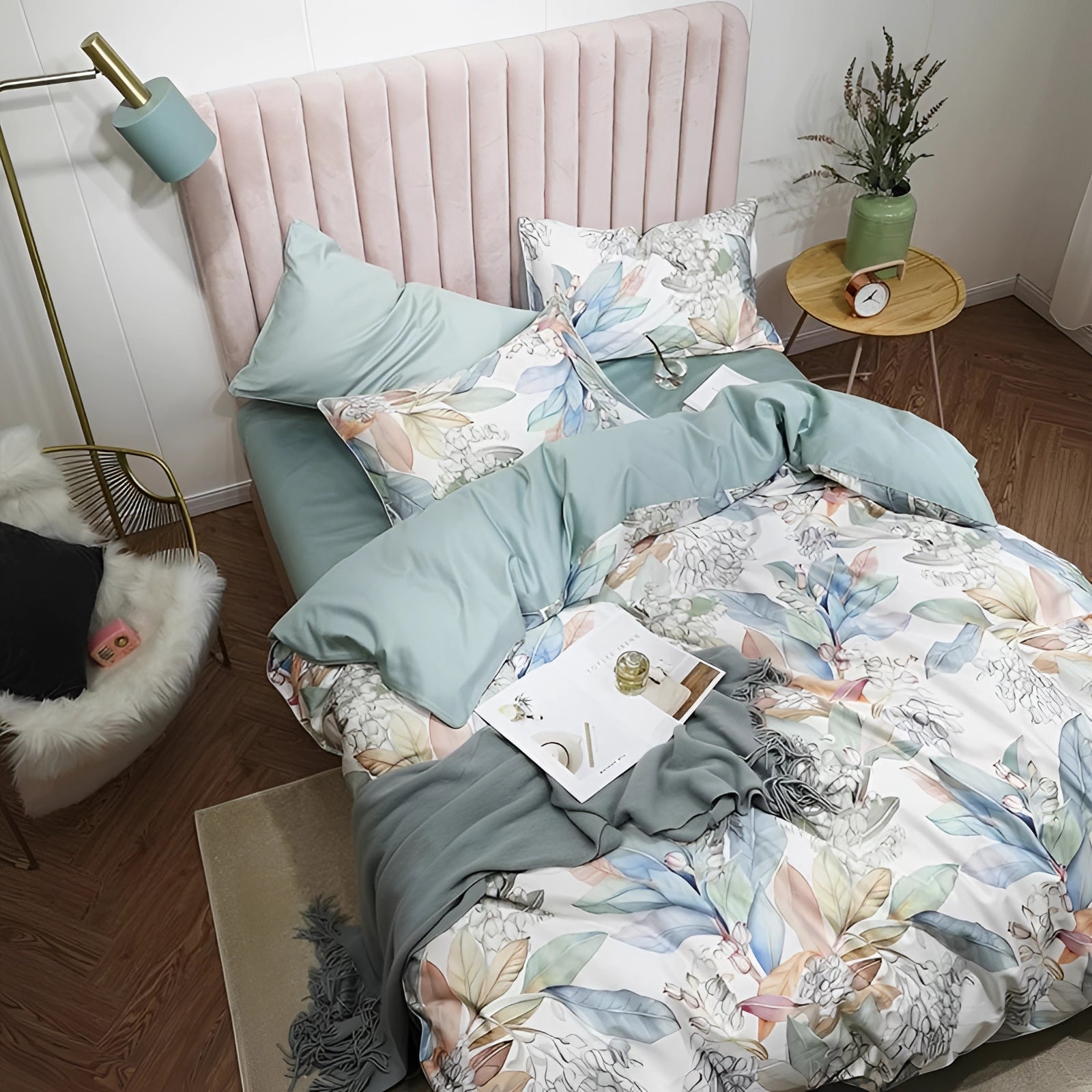 Luxury floral bedding set in pastel green, featuring a cotton duvet and pillowcase with a delicate floral pattern, styled in a cozy living room setting with a houseplant and a couch.