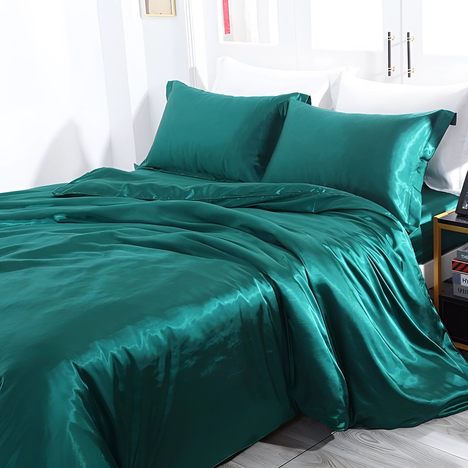 Luxury silk bedding set in ocean green, including fitted sheet, pillowcases, and duvet cover, displayed on a bed in a stylish, well-lit bedroom interior with wooden elements.