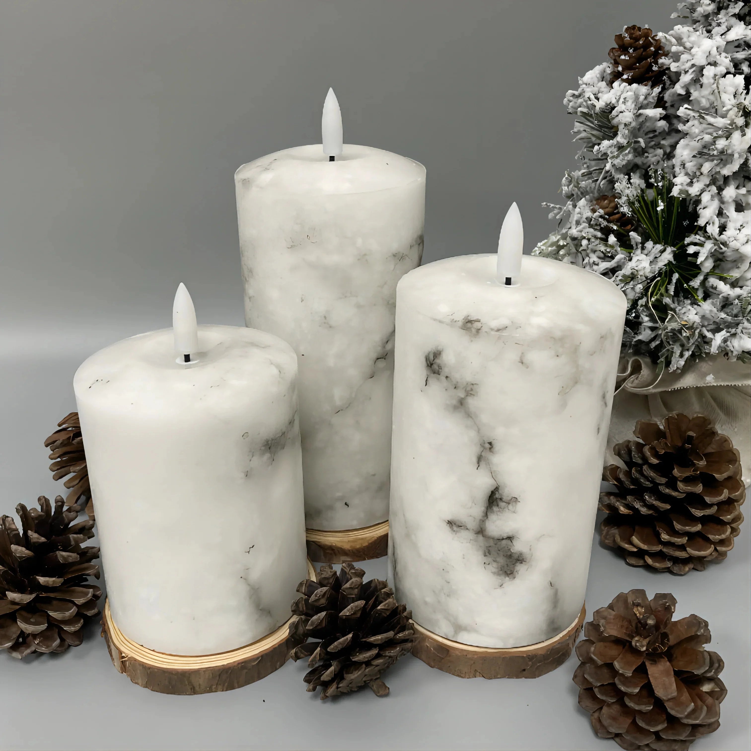 Flameless LED candles with marble design, placed on a white surface, accompanied by a remote control and battery-operated feature, resembling real wax, ideal for events.