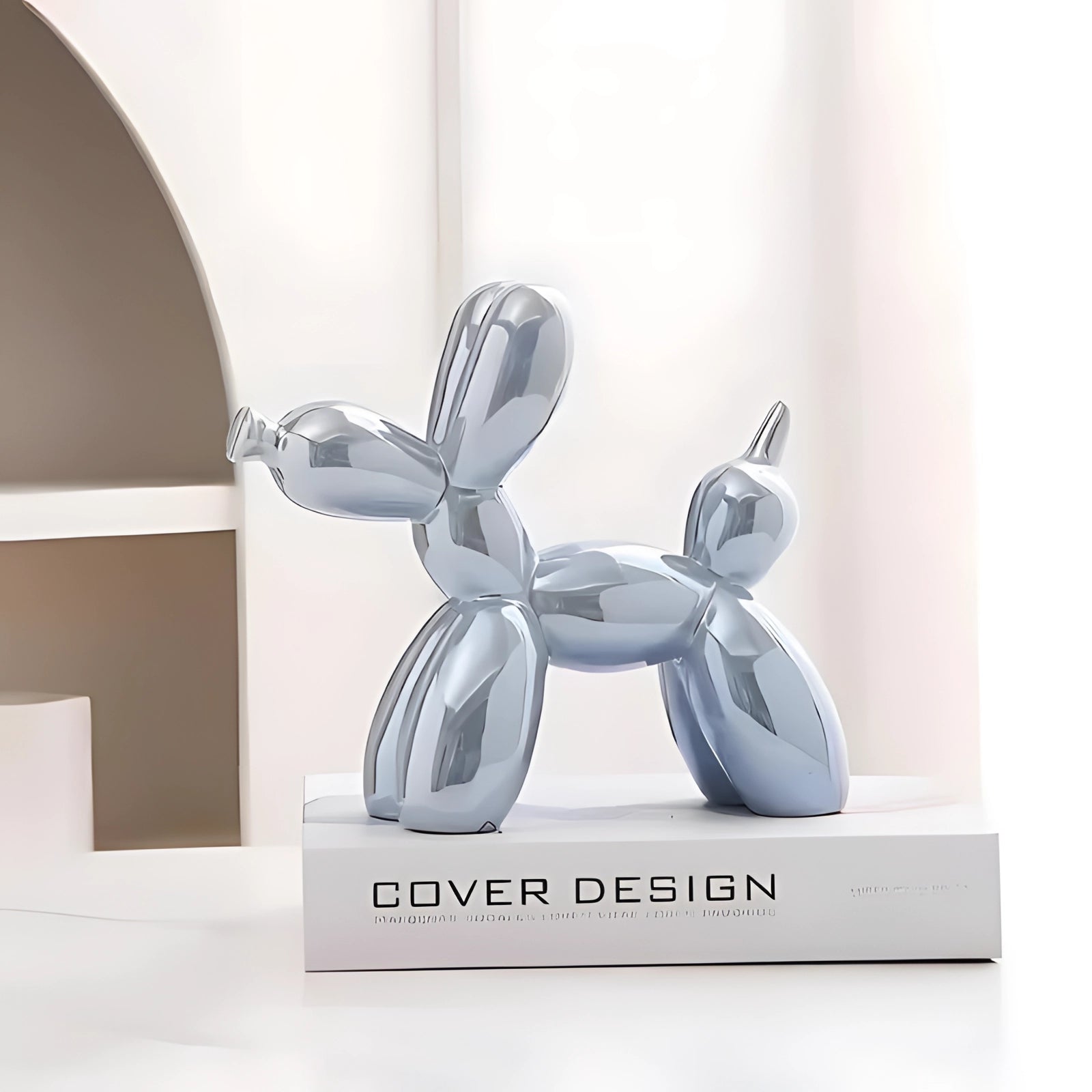 Metallic light blue balloon dog sculpture displayed as modern art decor, surrounded by minimalistic elements in an elegant setting.
