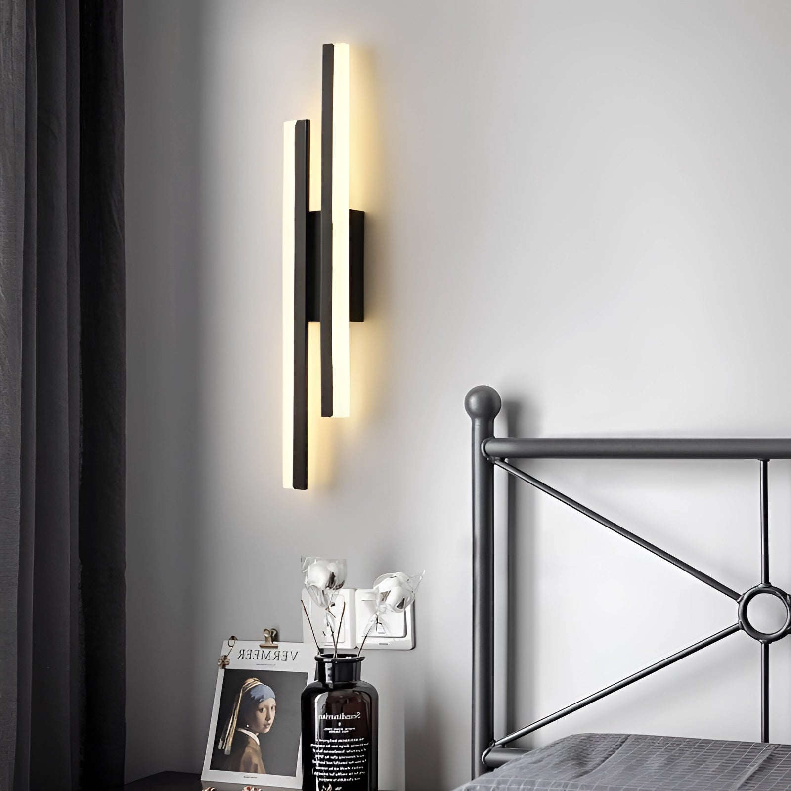 Minimalist black and white vertical line art framed in black, featuring sleek modern abstract design, displayed on a wooden rectangular background with visible glass and metal elements.