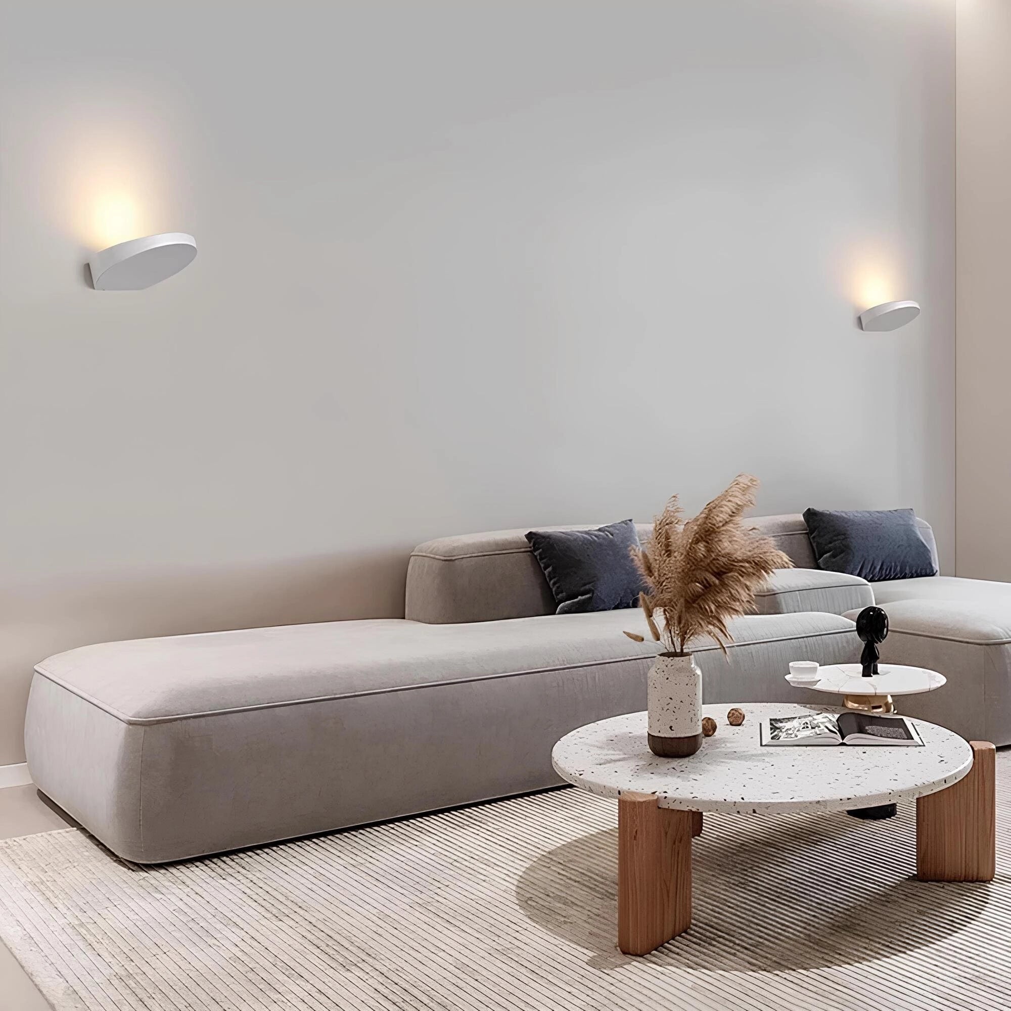 Gray minimalist sofa with a rectangular wooden coffee table and a beige rug, set in a modern living room interior design.