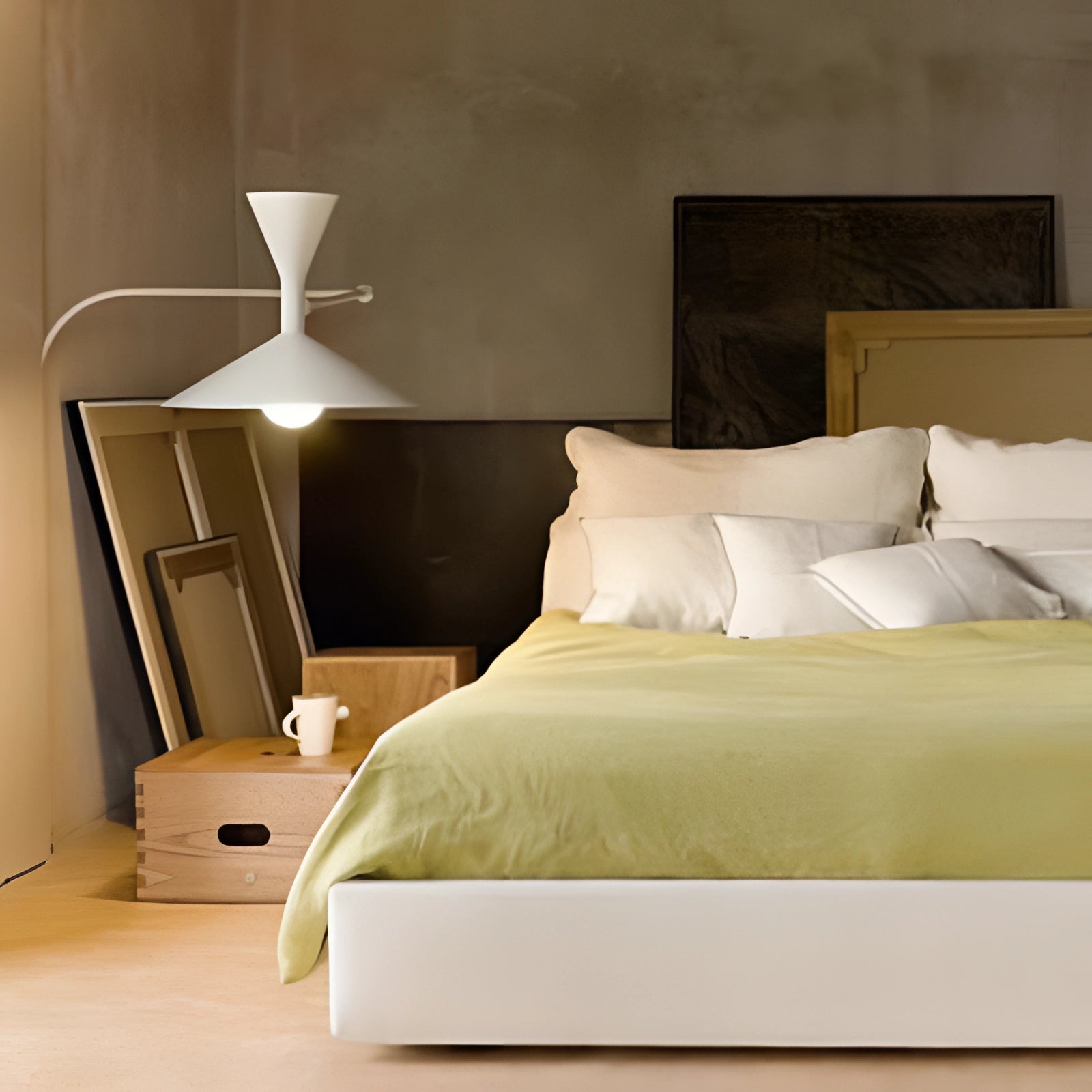 Modern black geometric wall sconce mounted on a wall, part of a contemporary minimalist interior design featuring a wooden bed frame with grey bedding and pillows.