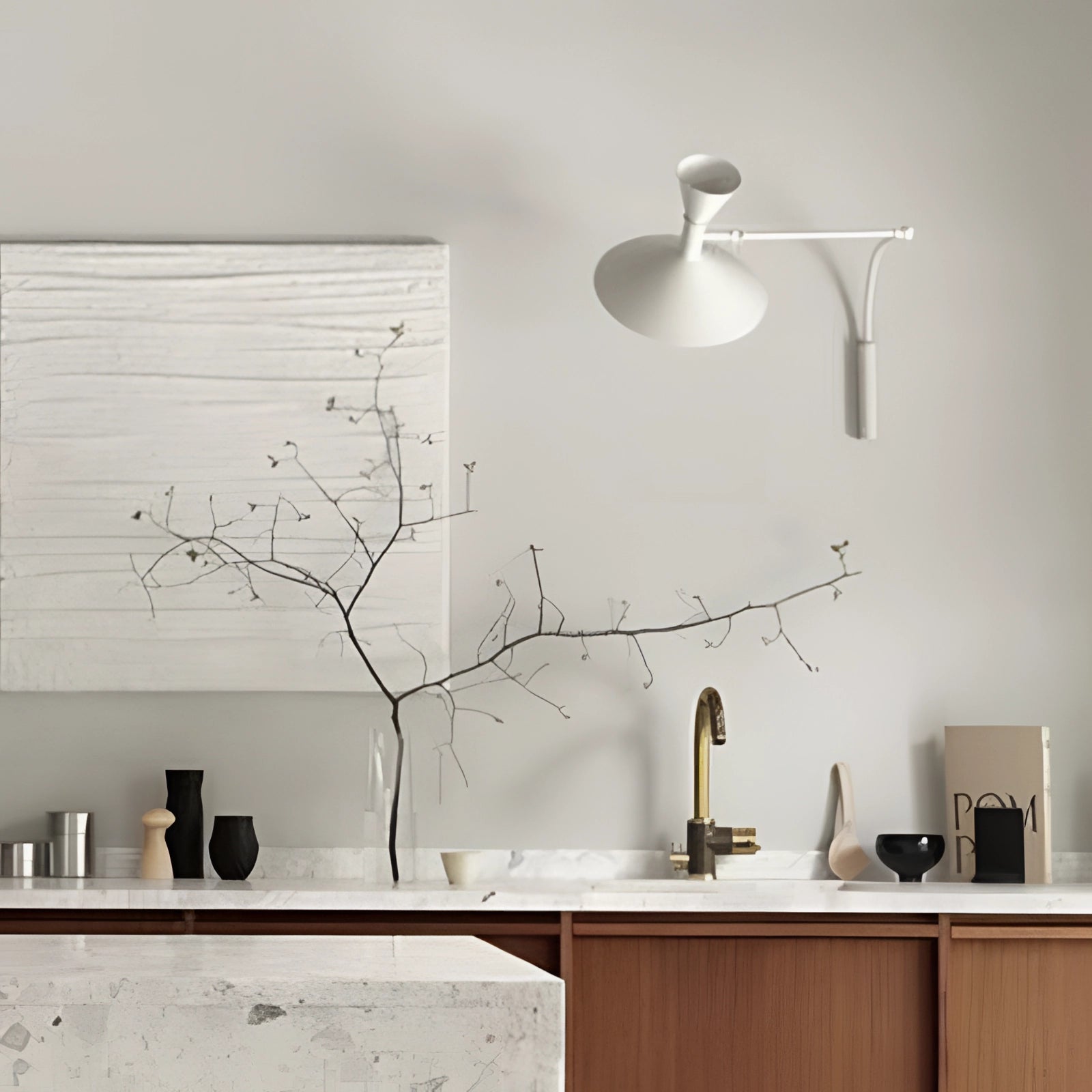 Modern black geometric wall sconce mounted on a white wall, with minimalist design elements including a sleek rectangular shape, situated above a wooden table with a small plant and twig arrangement, showcasing contemporary interior design aesthetics.