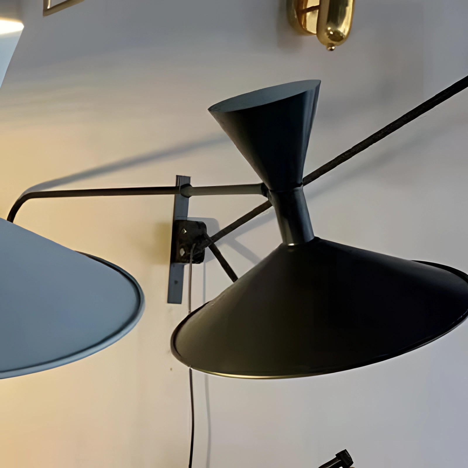 Modern black geometric wall sconce with a contemporary minimalist design, featuring a metal finish and sleek lines, mounted on a wooden background.