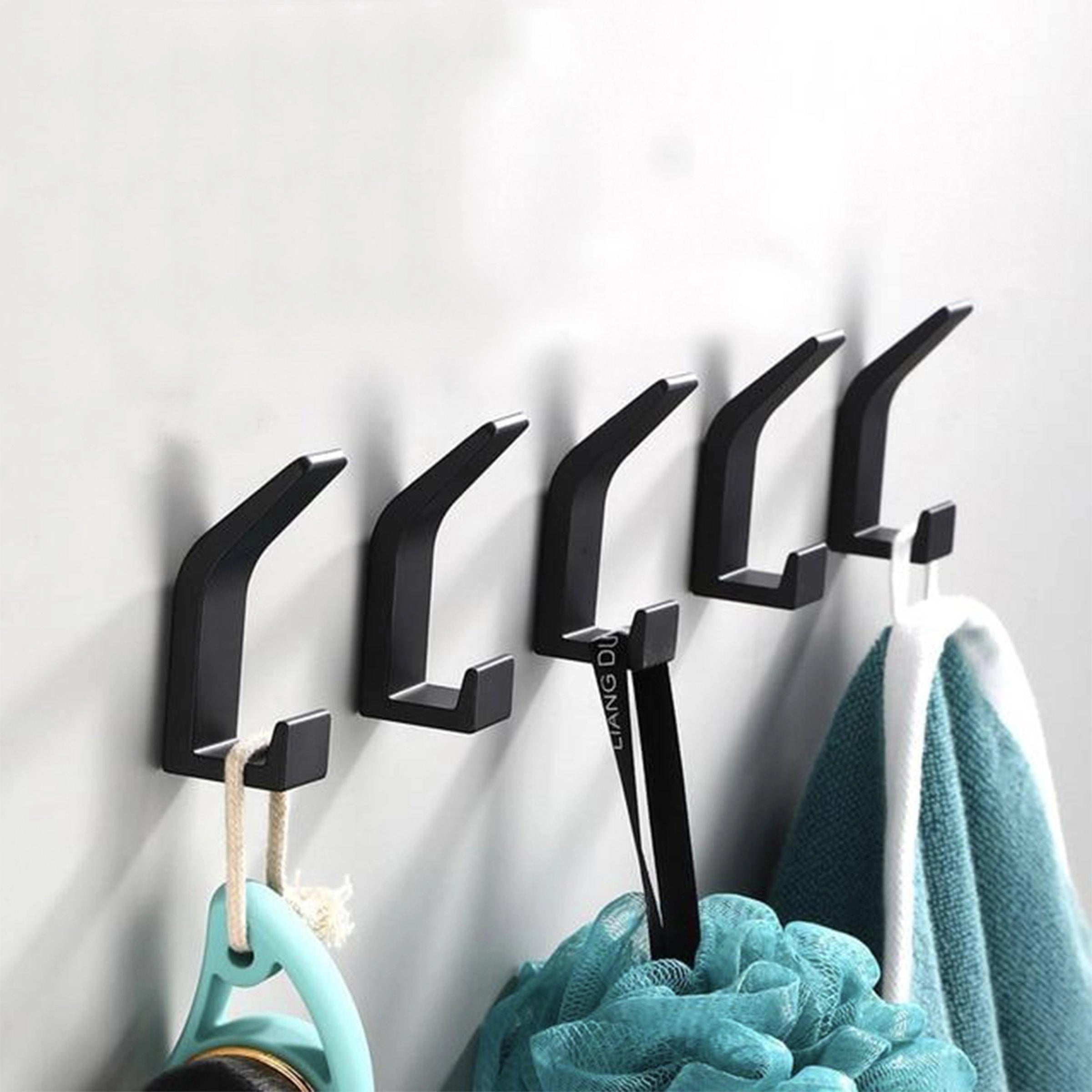 A set of modern black metal wall hooks mounted on a stylish wall, featuring a minimalist and sleek design, ideal for contemporary home decor.