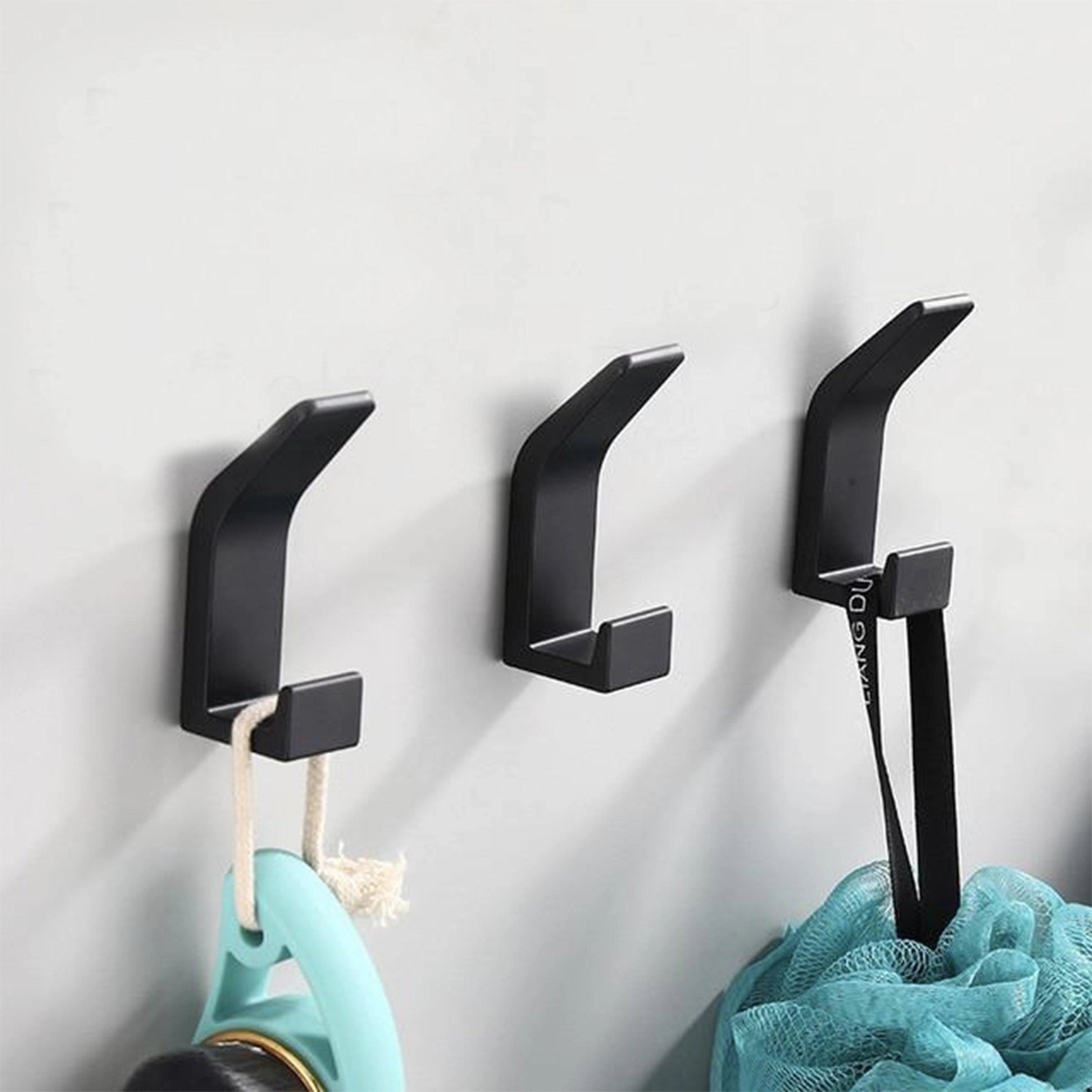 Stylish minimalist black metal wall hooks mounted on a white wall, showcasing a modern and sleek design suitable for contemporary home decor.