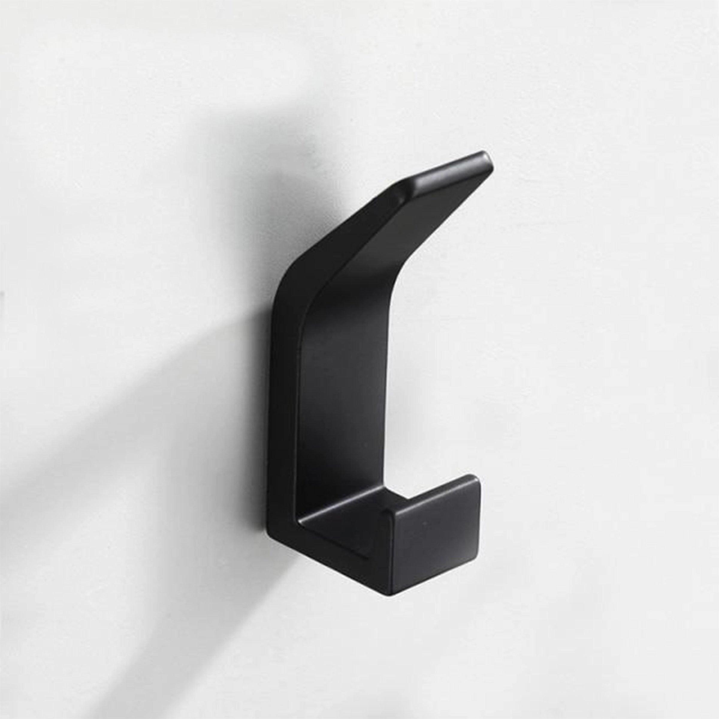 Modern black metal wall hook mounted on a white wall, showcasing its minimalist and stylish design. The hook has a sleek, rectangular shape that blends seamlessly into contemporary home decor.