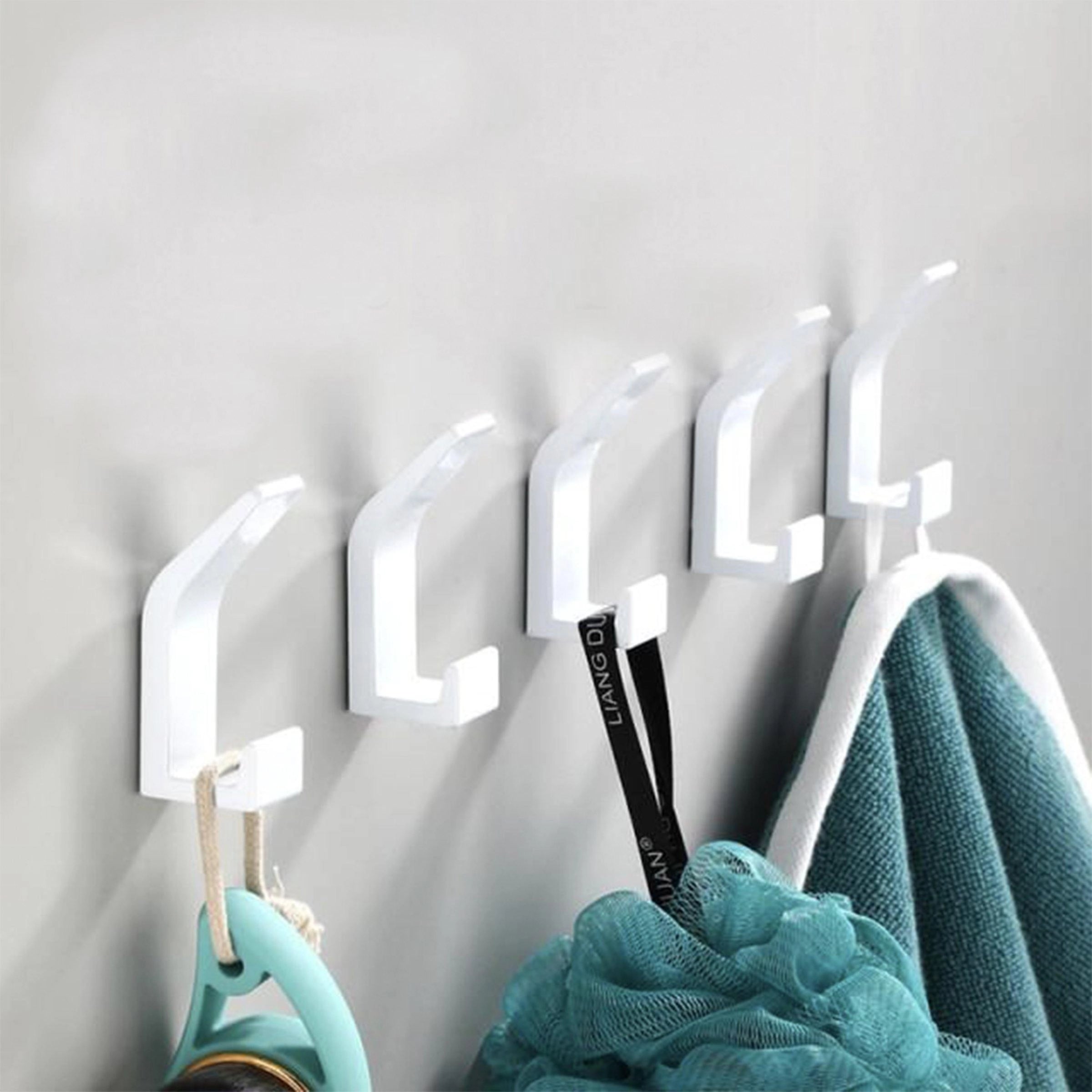 Modern black metal wall hooks mounted on a white wall, showcasing minimalist design and stylish home decor. The hooks have a sleek and contemporary appearance, ideal for organizing and enhancing the aesthetic of any space.