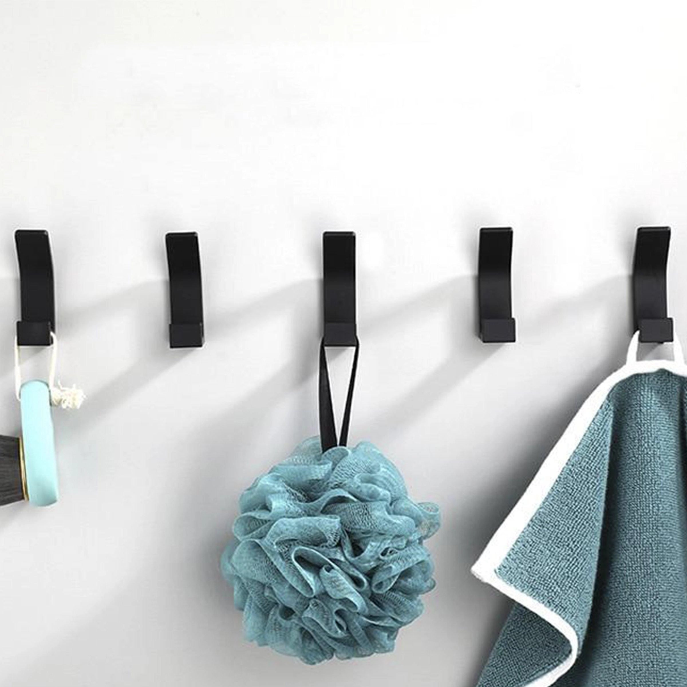Modern black metal wall hooks mounted on a white wall, showcasing a minimalist and stylish design suitable for home decor.