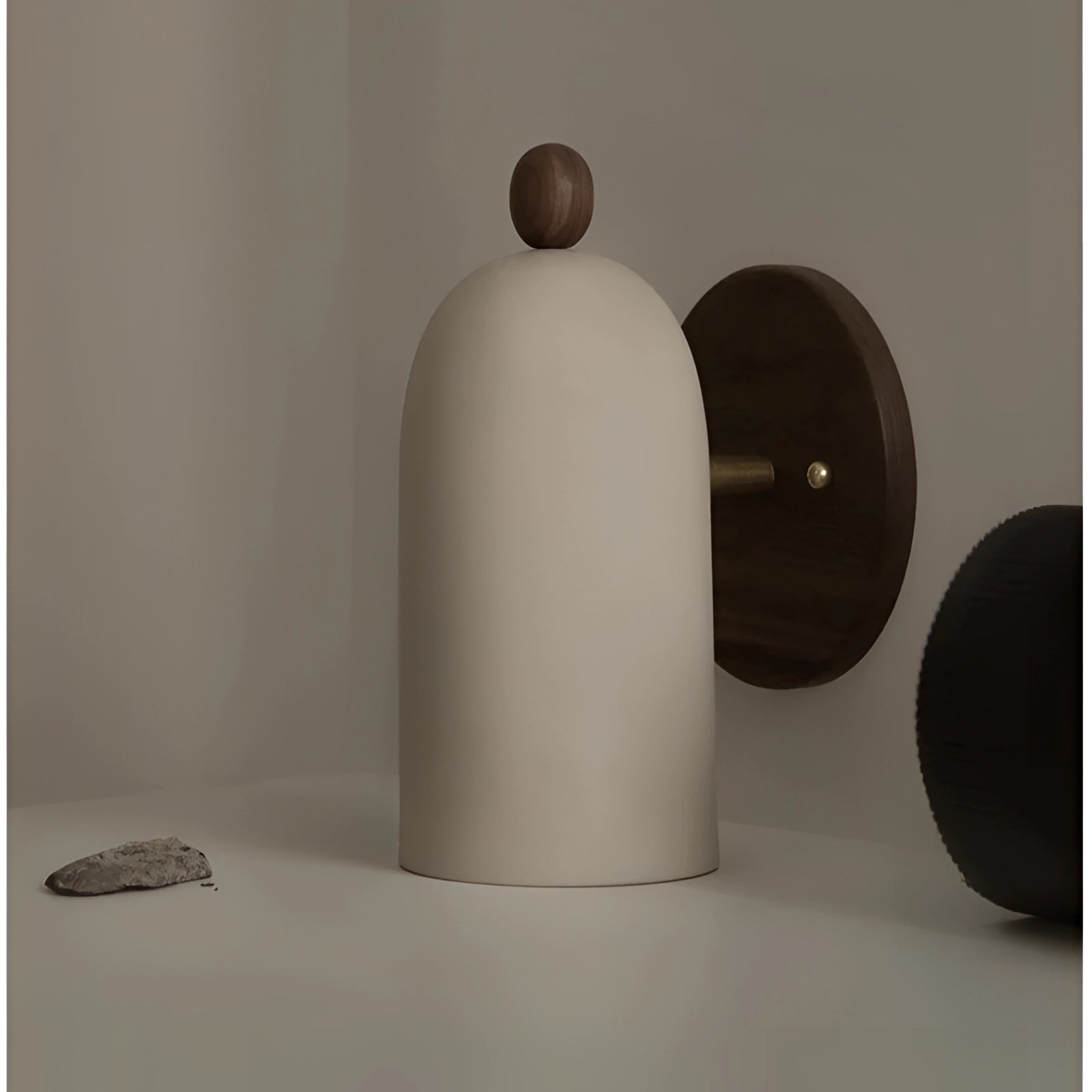 Modern black wall sconce with a minimalist industrial design, mounted on a wooden wall, showcasing sleek and elegant lines.