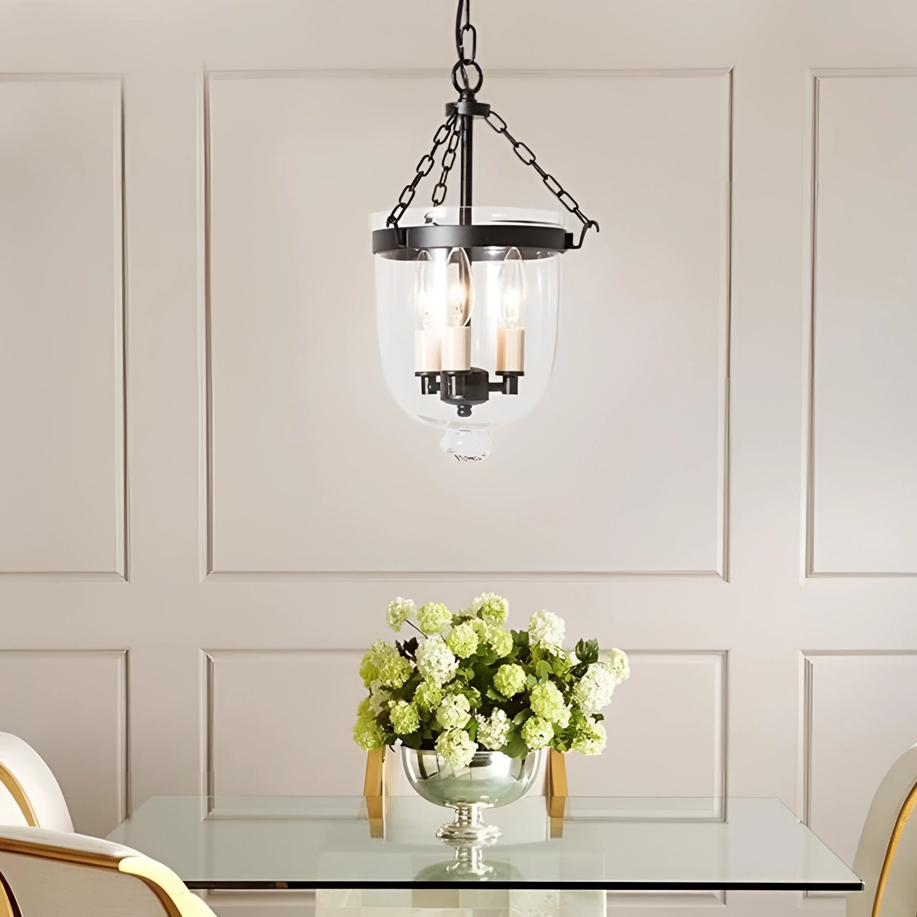 Modern brass glass pendant light chandelier hanging in a stylishly designed indoor space, featuring a rectangular wooden table adorned with a vase of flowers, highlighting the elegant interior design.