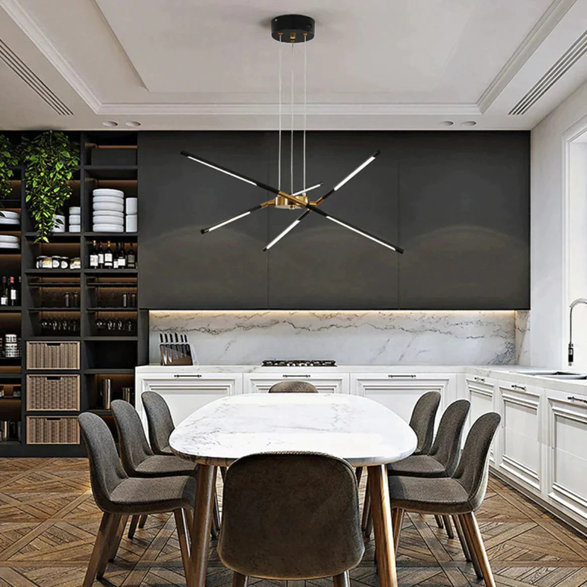Modern brass LED chandelier hanging above a luxurious dining table with white and black chairs, wood cabinetry, and elegant interior design elements.