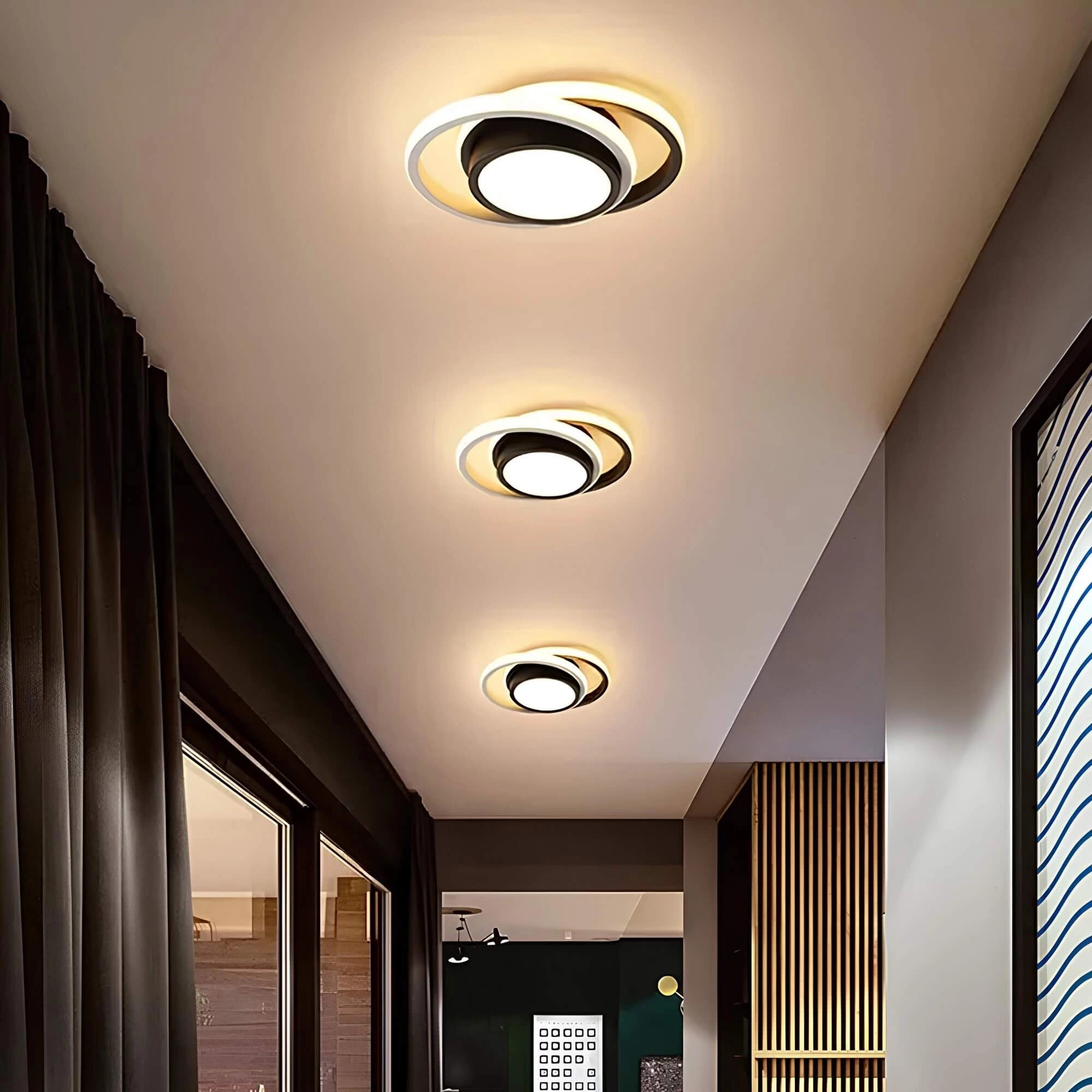 Modern circular LED ceiling light with a minimalist design, mounted on a ceiling, illuminating a room with wooden accents and curtains.