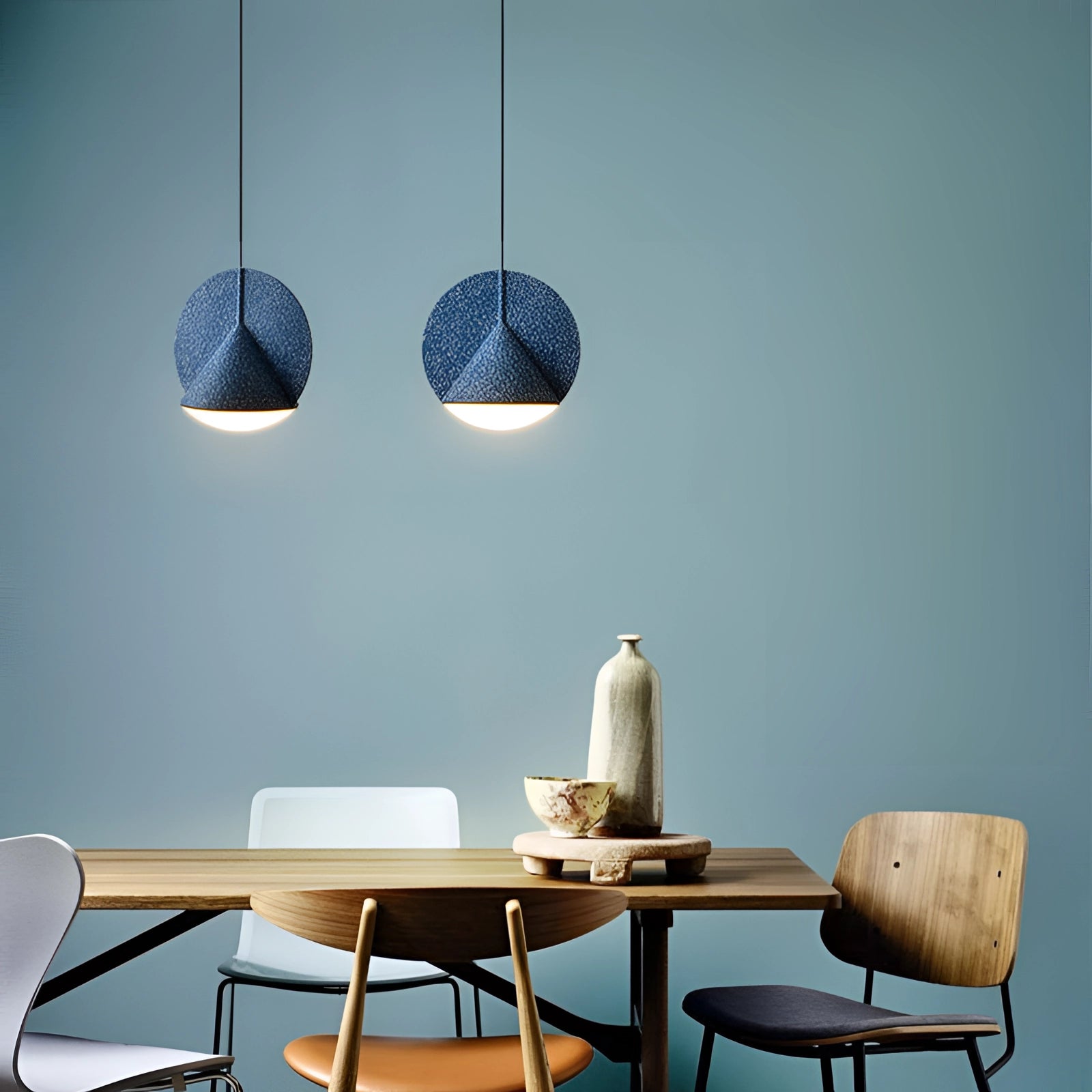 Modern colorful fabric pendant lights hanging above a wooden table in a contemporary interior design setting.