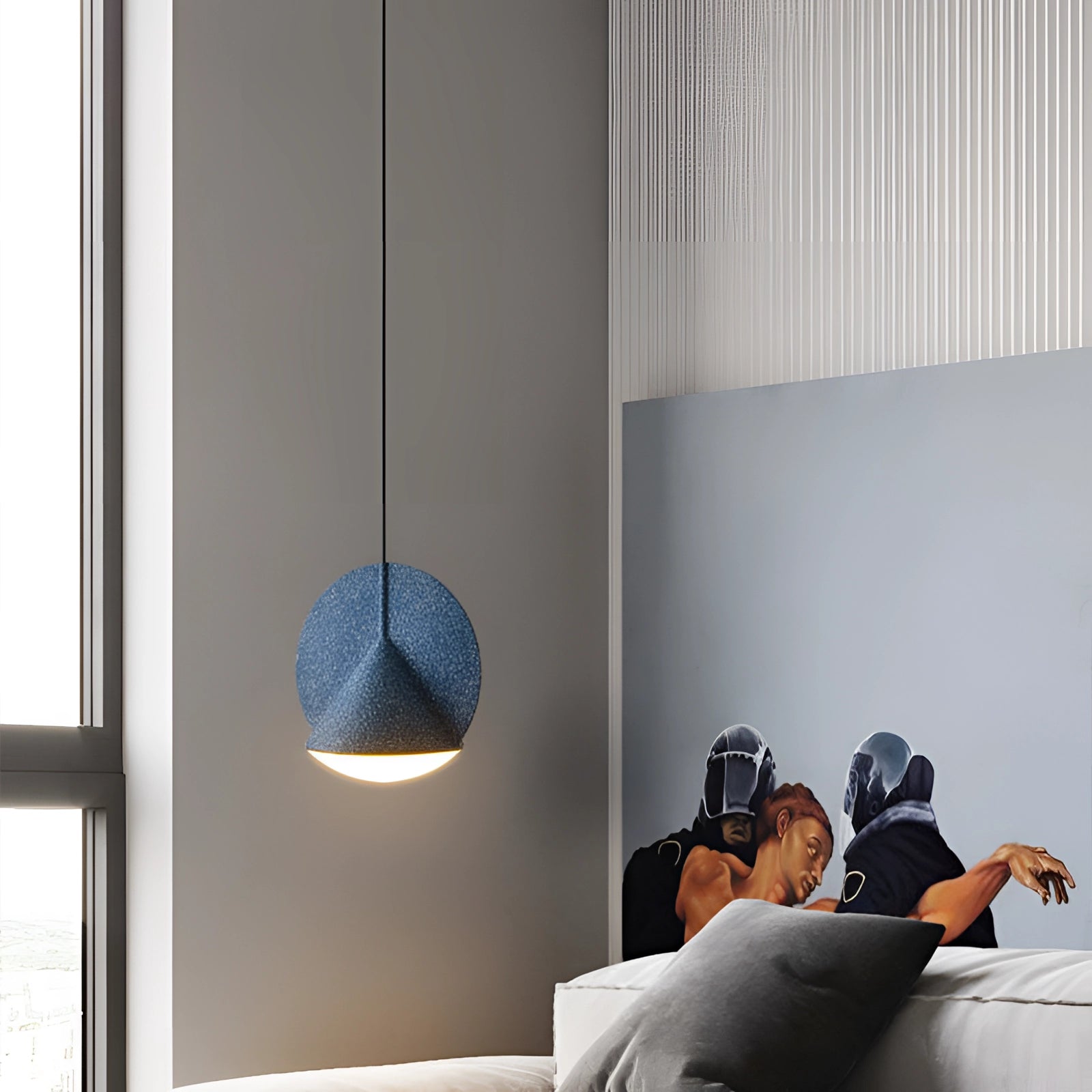Modern colorful fabric pendant light in blue, hanging from the ceiling, illuminating a contemporary interior design setting.