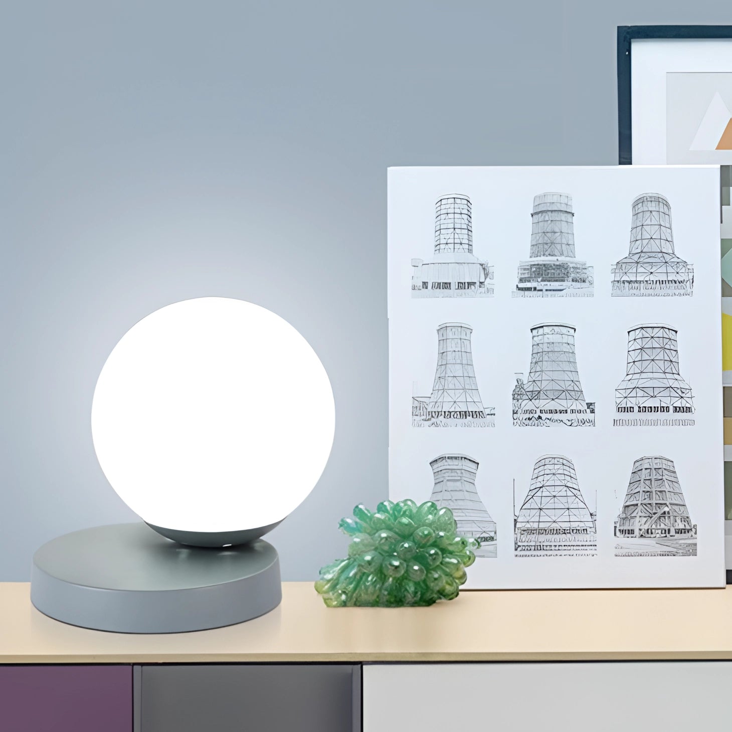 Modern designer orb lamp with LED globe and metallic base placed on a rectangular surface, accompanied by a decorative plant in a flowerpot in a stylish room setting.