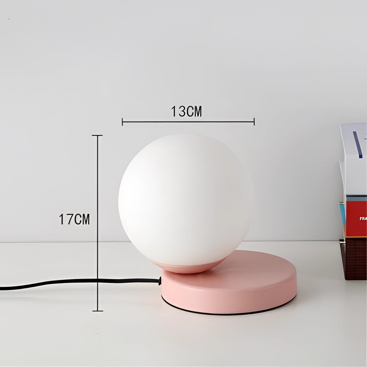 Modern pink designer orb lamp with a metallic base, featuring an LED globe in a circle shape, set against a transparent background.