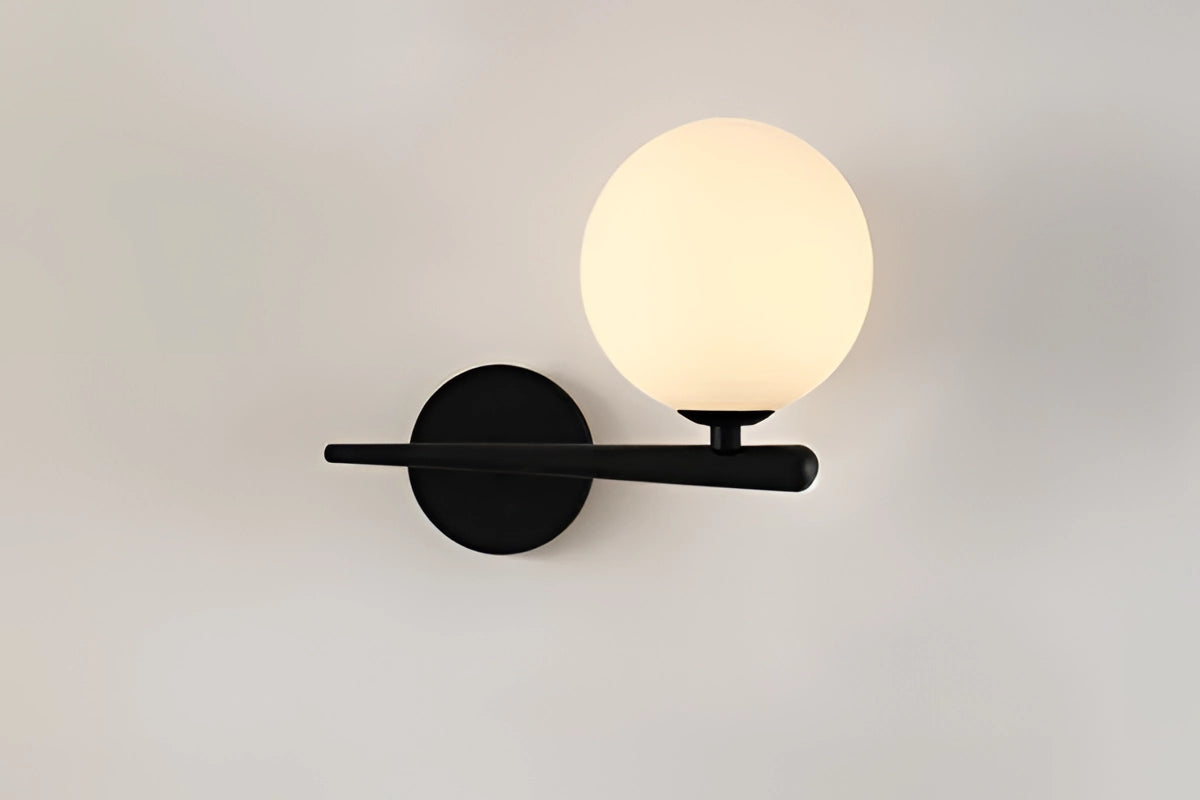 Modern dual globe brass wall sconces with a minimalistic design, featuring circular glass shades and a sleek brass finish, mounted on a wall and illuminating the space with a warm glow.