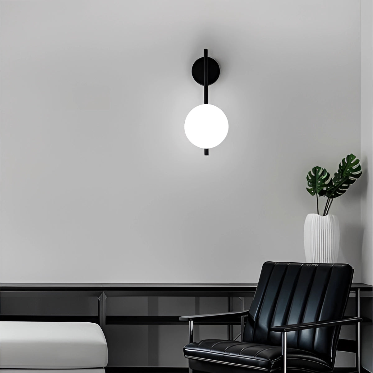 Modern dual globe brass wall sconces mounted on a minimalist interior wall, featuring a sleek design that enhances the contemporary decor of the room. The sconces complement the black-and-white theme and add a touch of elegance to the furniture and art elements present.