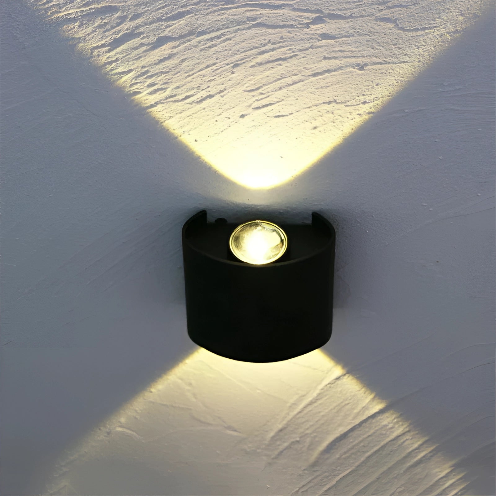 A black modern geometric LED wall sconce mounted on a wall, emitting ambient light. The design features a sleek, rectangular shape with a waterproof finish, suitable for both indoor and outdoor use. The light adds a subtle glow to the surrounding area.
