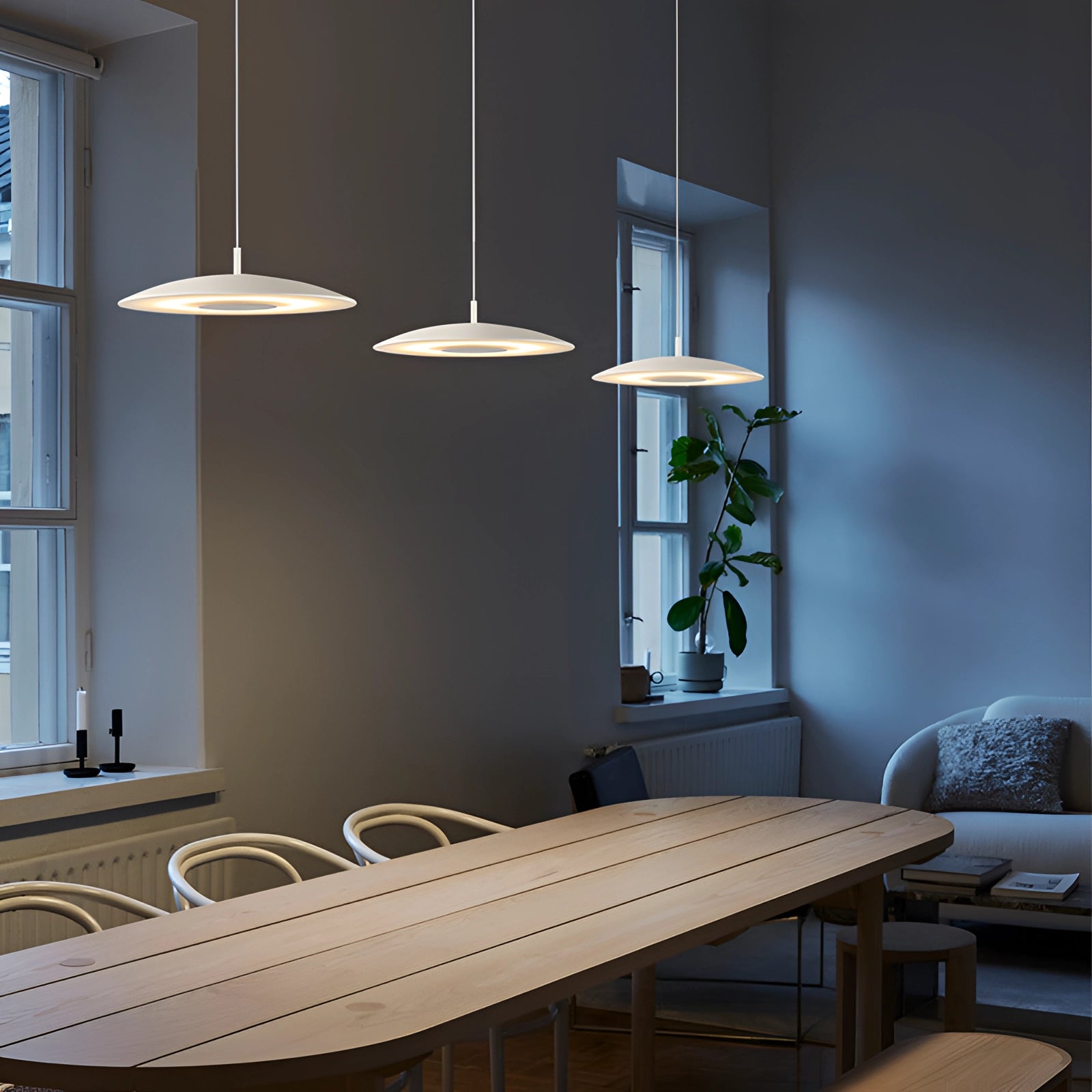 Modern gold-brushed pendant light with a sleek design, featuring a white finish and a diameter of 15.7 inches, hanging above a dining table in an elegantly styled interior with wooden flooring.
