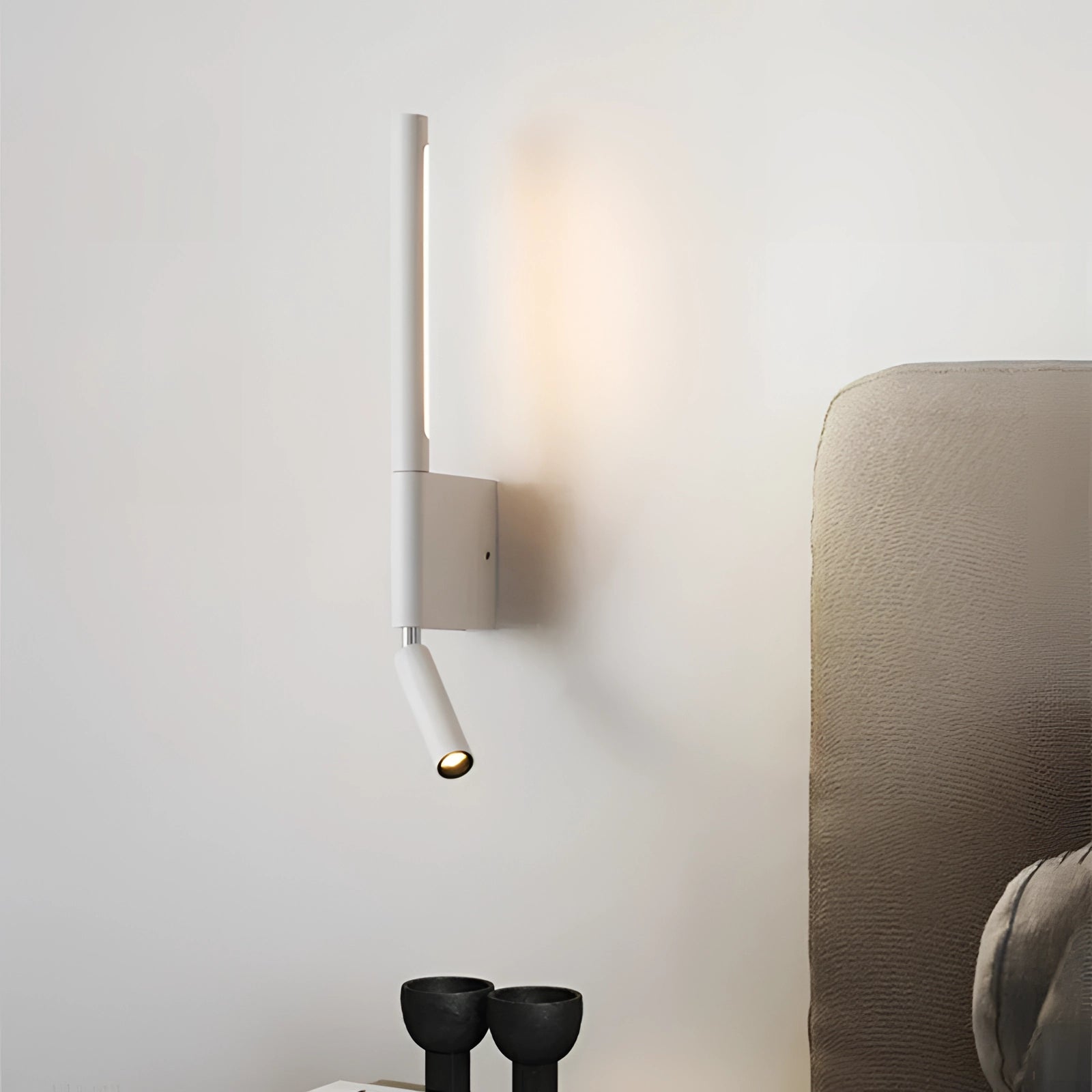 Modern LED wall lamp in a minimalist style, featuring a white finish and designed for luxury bedroom lighting. The lamp emits a daylight glow and includes a cylindrical lampshade, mounted on a wooden element that complements contemporary decor.