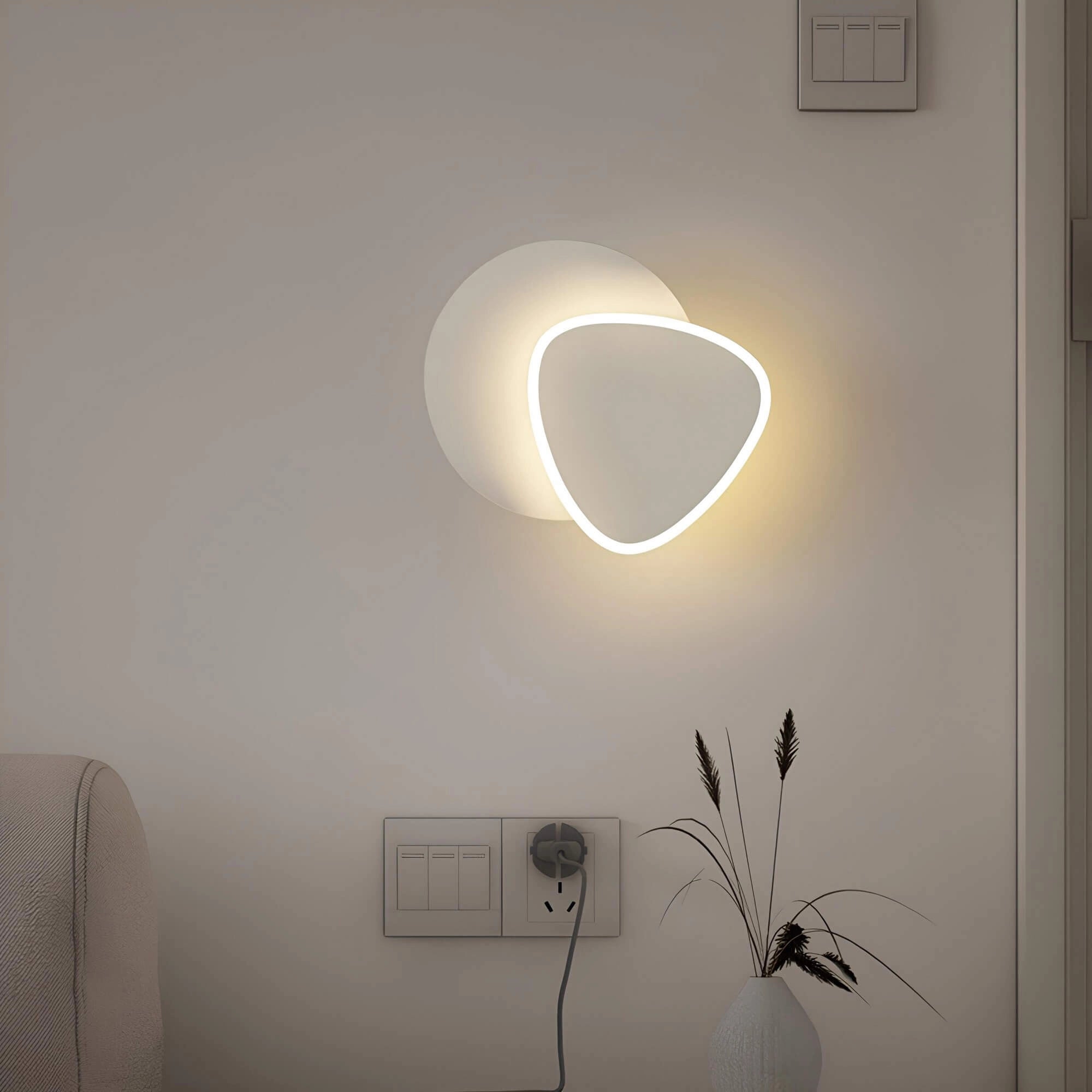 Modern LED wall sconce featuring a geometric minimalist design with circular and rectangular shapes, presented in shades of grey, mounted on an indoor wall.