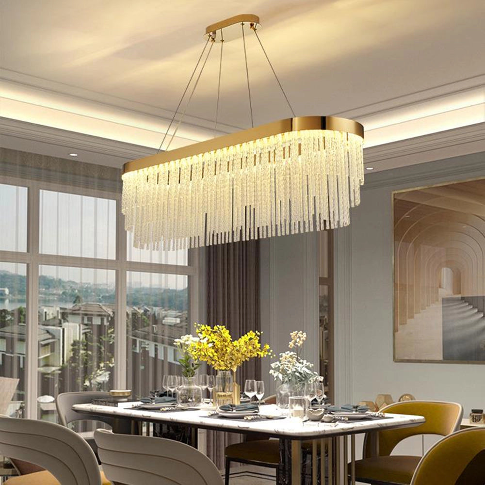 Modern luxury circular crystal LED chandelier with a brass finish, measuring 31.5 inches in length, elegantly hangs over a dining table set with chairs, tableware, and decorative elements like plants and flowers.