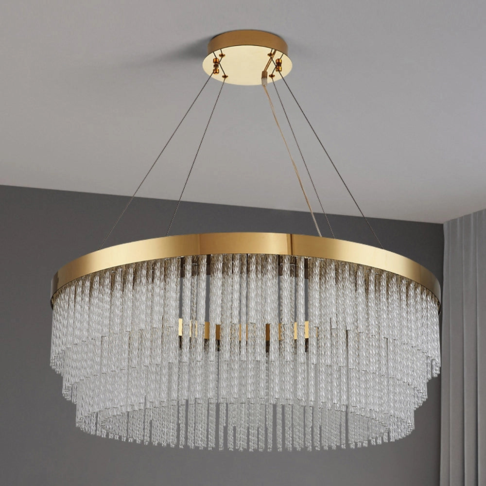 Modern luxury circular crystal LED chandelier with a brass finish hanging elegantly in a room, showcasing its intricate design and bright illumination. The chandelier features multiple crystal elements and a circular shape, complementing the stylish setting with wooden accents.