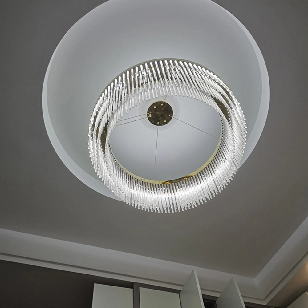 Modern circular LED chandelier with crystal accents and a brass finish, suspended from the ceiling, featuring a sleek and artistic design.