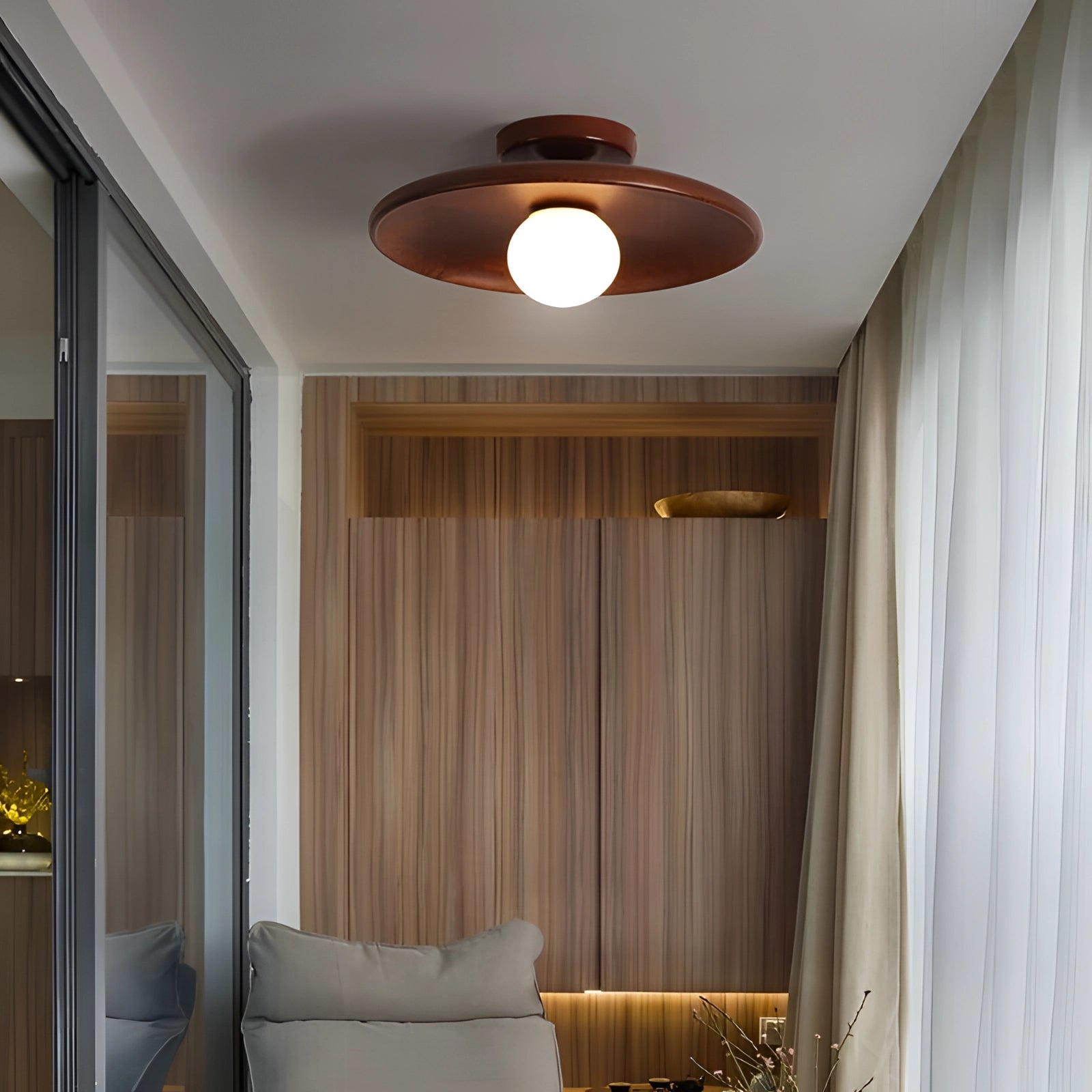 Modern minimalist wooden ceiling light with warm-tone shade, providing soft ambient glow in a cozy interior setting.