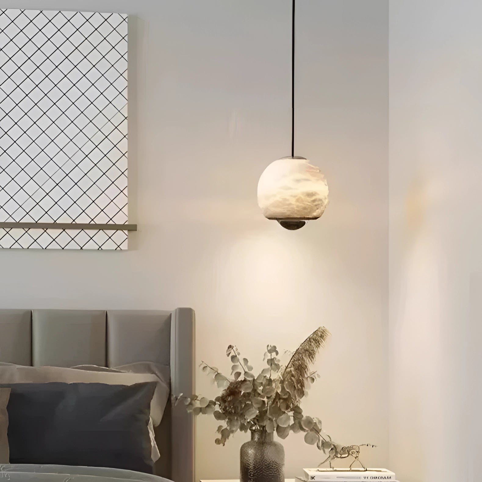 Modern minimalist white spherical pendant light hanging in a stylish bedroom with houseplants, a flowerpot, a couch, a wooden floor, and a large window.
