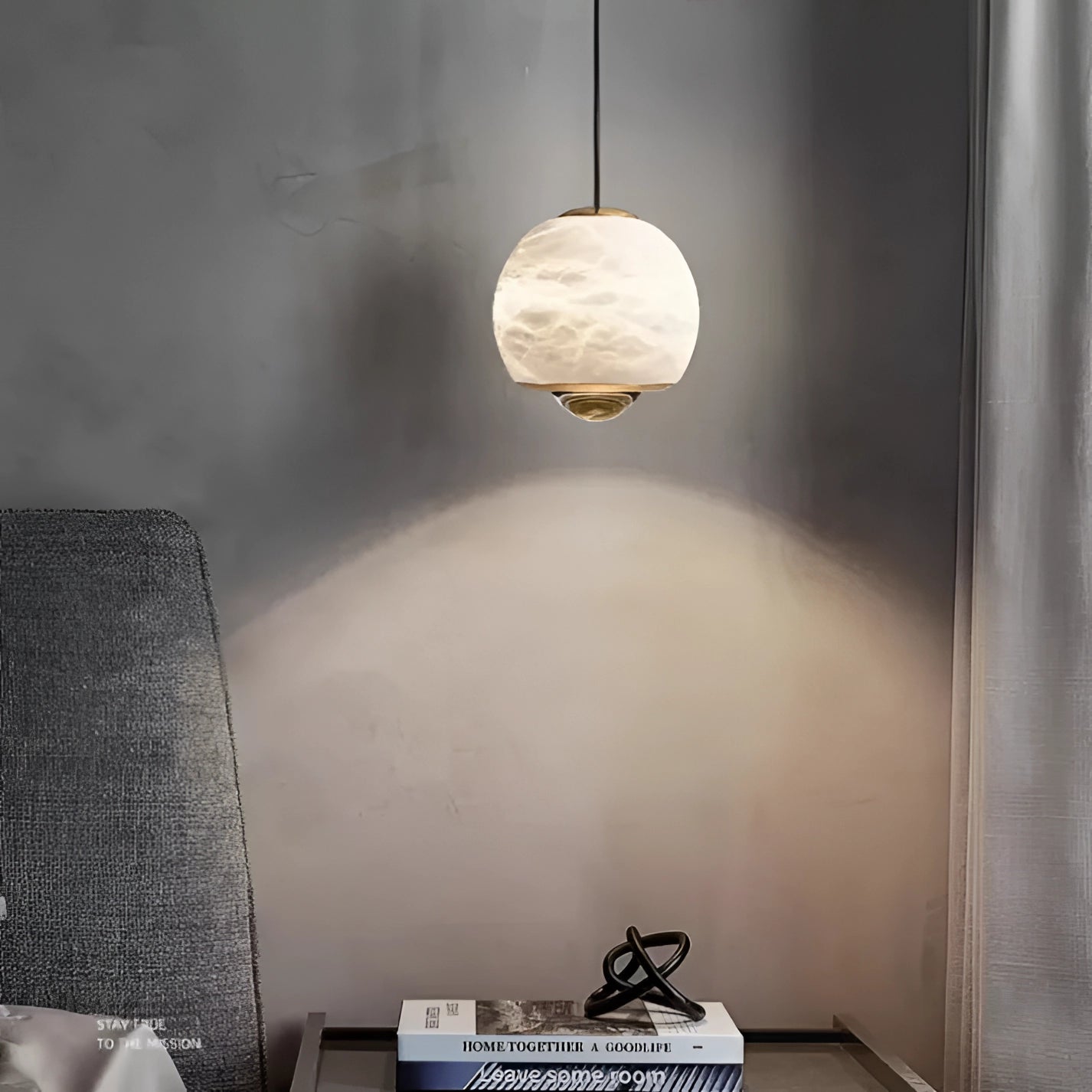 Modern minimalist white spherical pendant light hanging from the ceiling, with a wooden accent, illuminating a stylish bedroom decor with neutral tones.