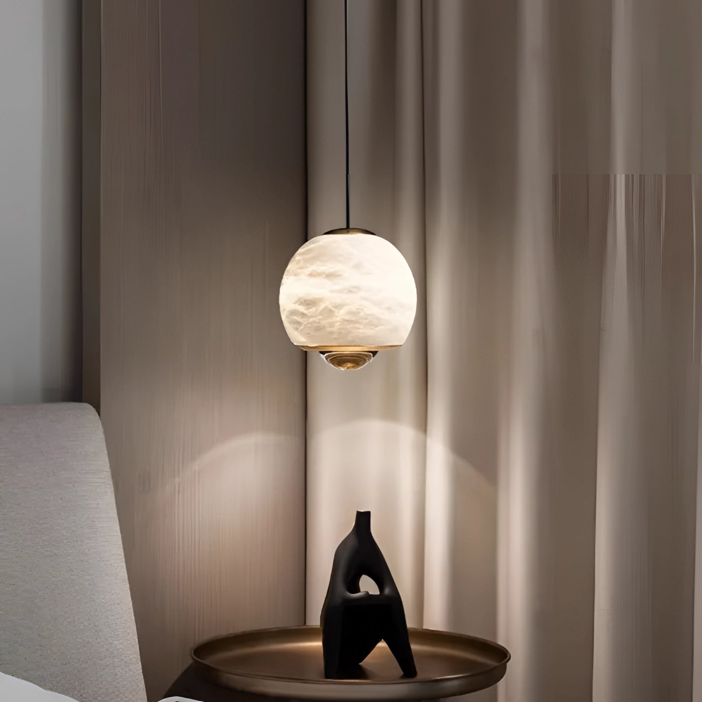Modern minimalist white spherical pendant light hanging from the ceiling in a stylish bedroom with hardwood floors, adding a touch of comfort and sophistication to the interior design.