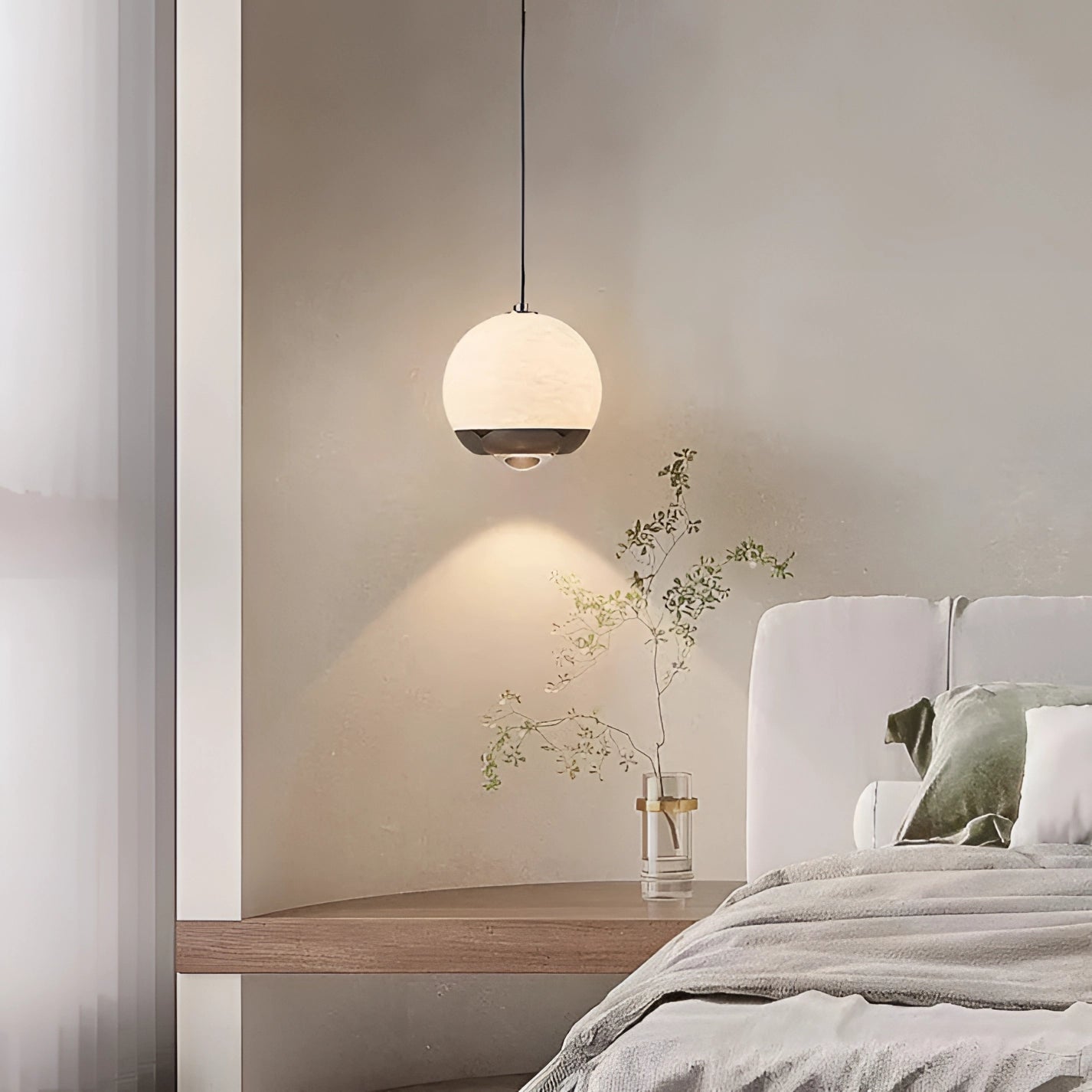 Modern minimalist white spherical pendant light hanging in a bedroom with wooden furniture and hardwood flooring.