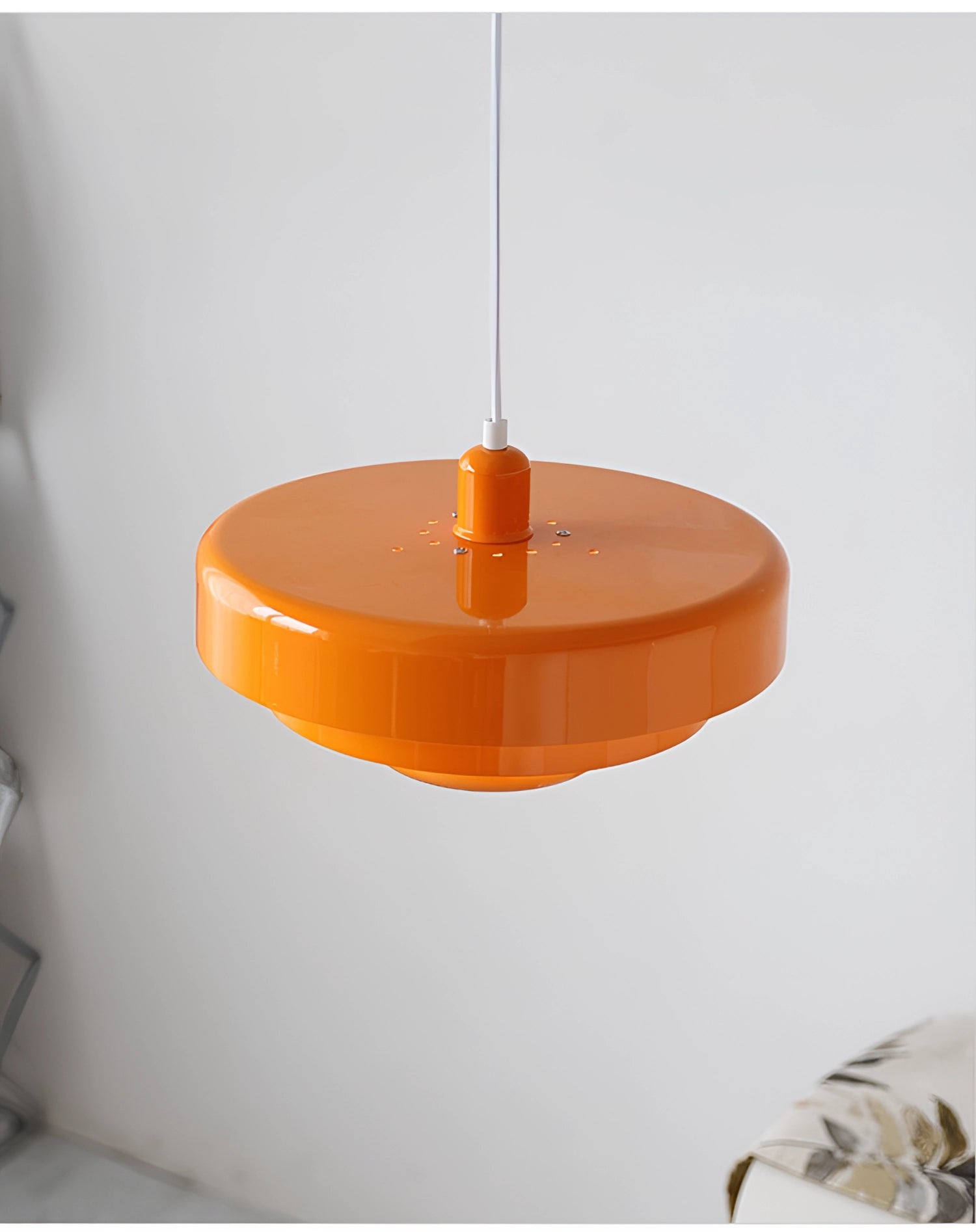 Modern orange pendant light with a smooth cylindrical shape, hanging from the ceiling, designed in Scandinavian and mid-century contemporary style.