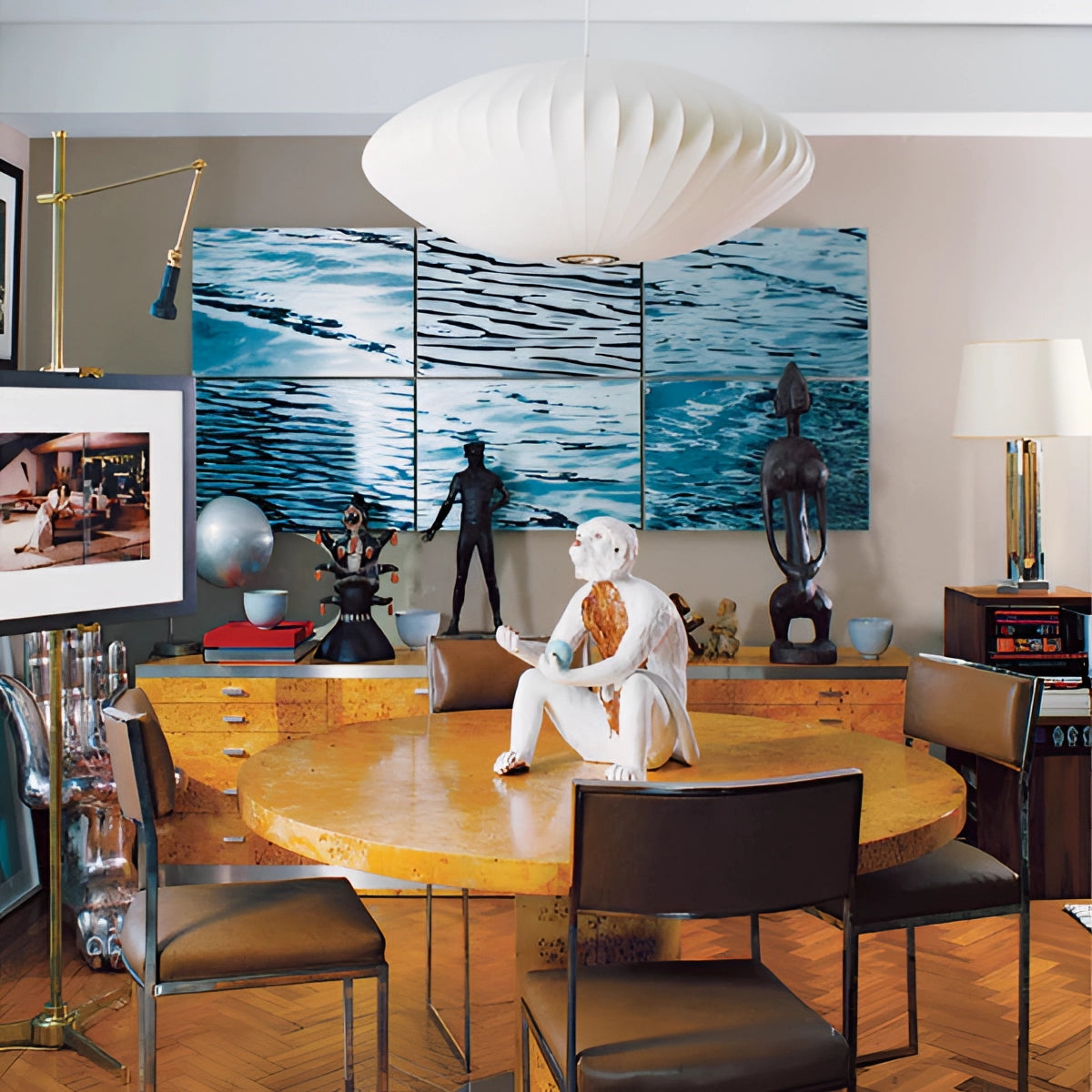 Modern oval pendant lights hanging above a contemporary dining room setting with a wooden table and chairs, featuring elements of interior design such as picture frames and a stylish lamp, complemented by wooden flooring.