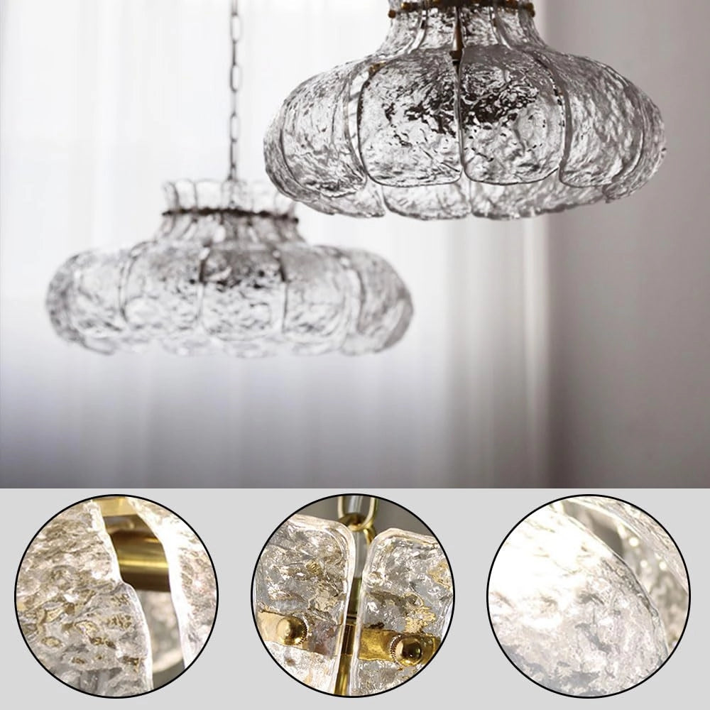 Modern pear-shaped glass chandelier with a luxurious design, featuring a gold chain and glass elements that reflect light, creating an elegant ambiance. The chandelier is predominantly white with hints of silver and natural material textures.