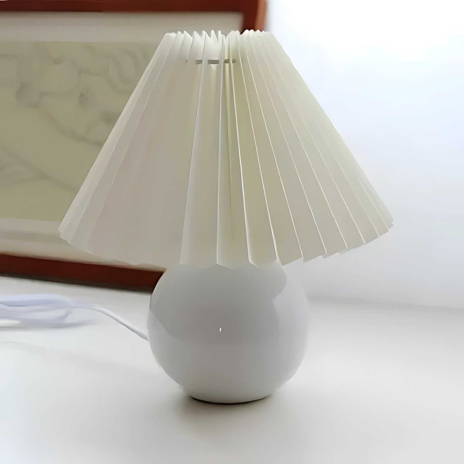Modern white ceramic lamp with pleated shade, featuring Scandinavian design, placed on a wooden table.