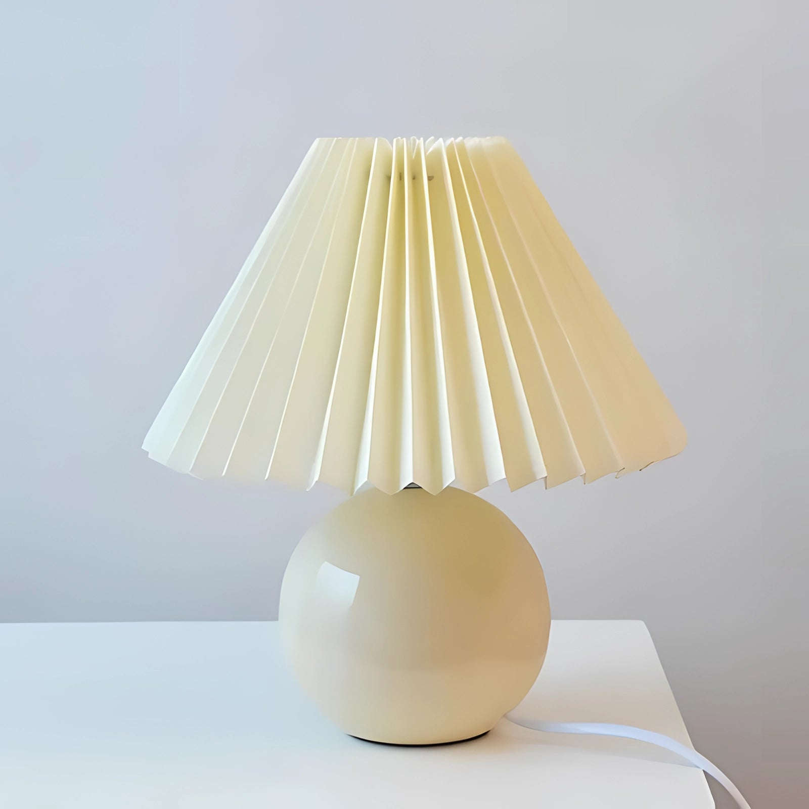 Modern pink ceramic lamp with an all-cream pleated shade, featuring a Scandinavian design aesthetic with beige tones. The lamp showcases a blend of artful design and material properties, ideal for contemporary interiors.
