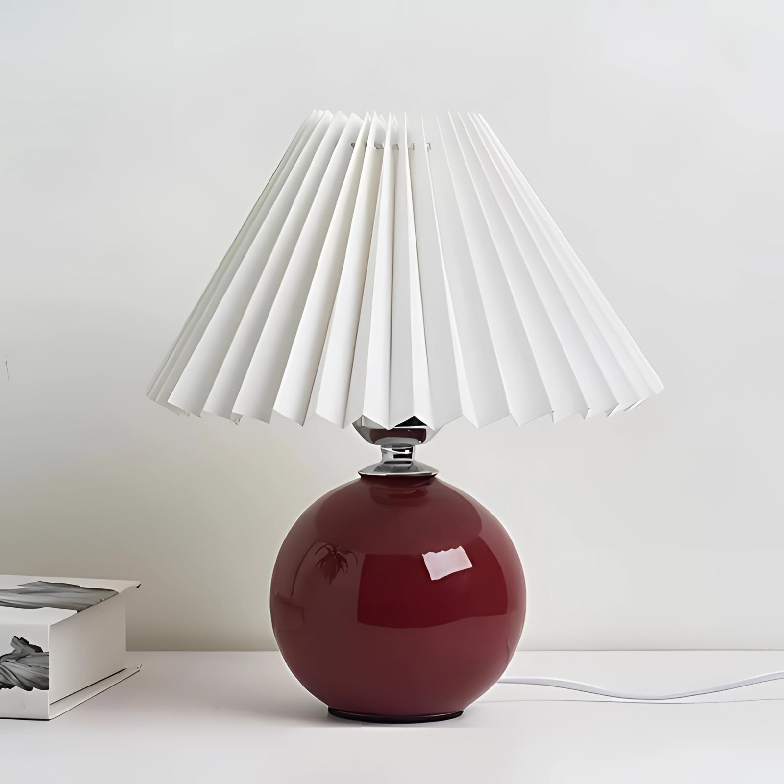 Modern pink ceramic lamp with a pleated shade featuring Scandinavian design elements, highlighting a white and red color variant. The lamp is an artful combination of material property and tints and shades, ideal for adding a contemporary touch to any room.