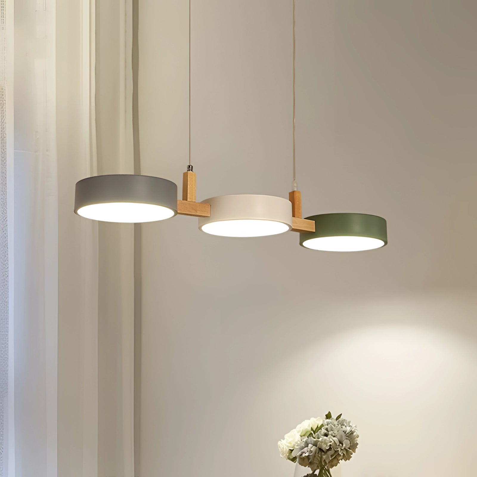 Modern Scandinavian adjustable triple pendant lights hanging from the ceiling in a dining room with a clean, minimalist interior design featuring wood accents and neutral tones.