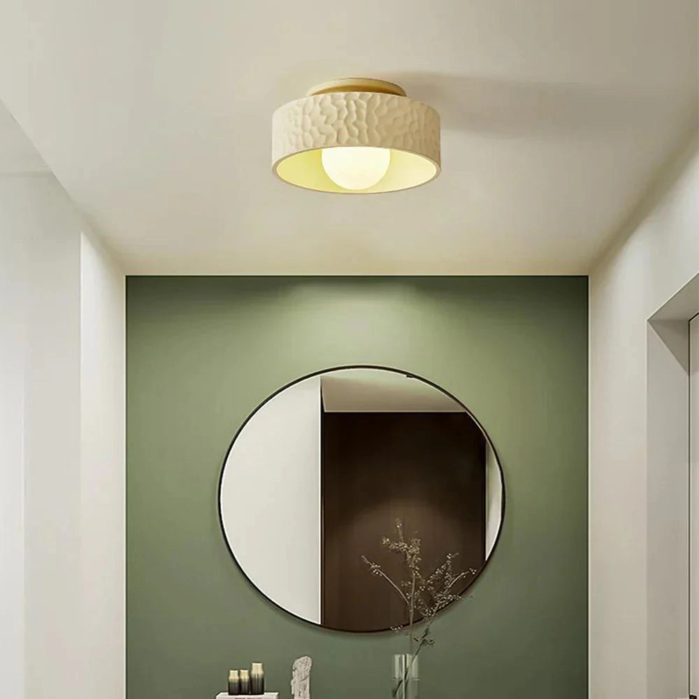 Modern beige circular LED ceiling light with a textured design, flush-mounted on a ceiling in a stylishly designed interior space.