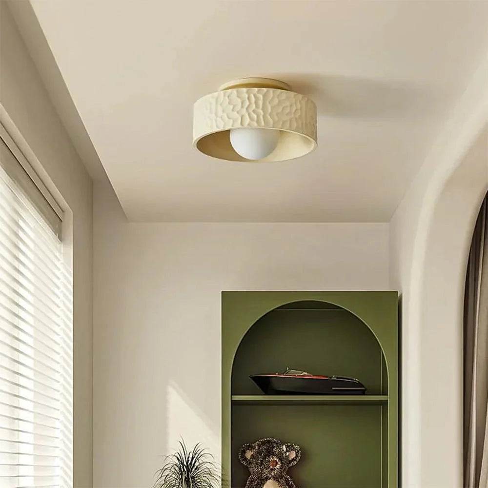 Modern textured circular LED ceiling light fixture with a flush mount design, installed in a contemporary interior setting featuring wooden elements and sleek architectural details.