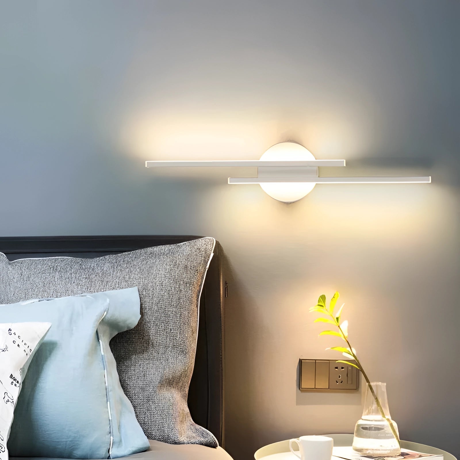 Modern black circular LED wall sconce with a minimalist design, mounted on a grey wall, providing ambient lighting in an interior setting.